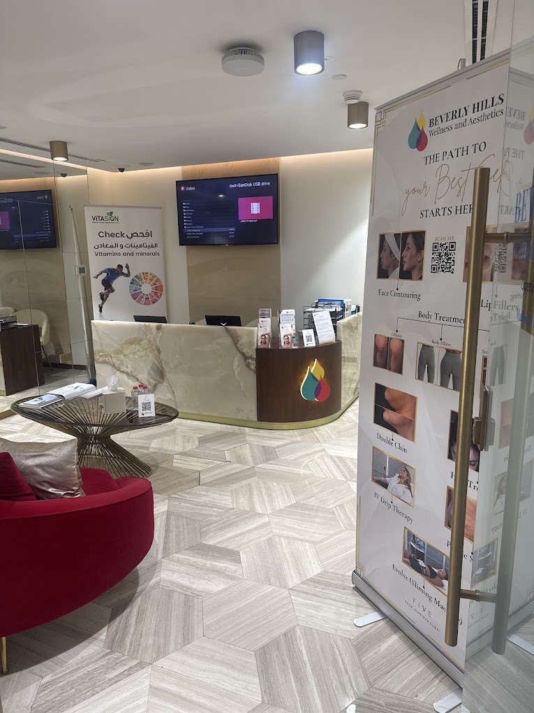 Reception area with a curved desk, digital screens, and a standing display with images and text, in a modern interior.