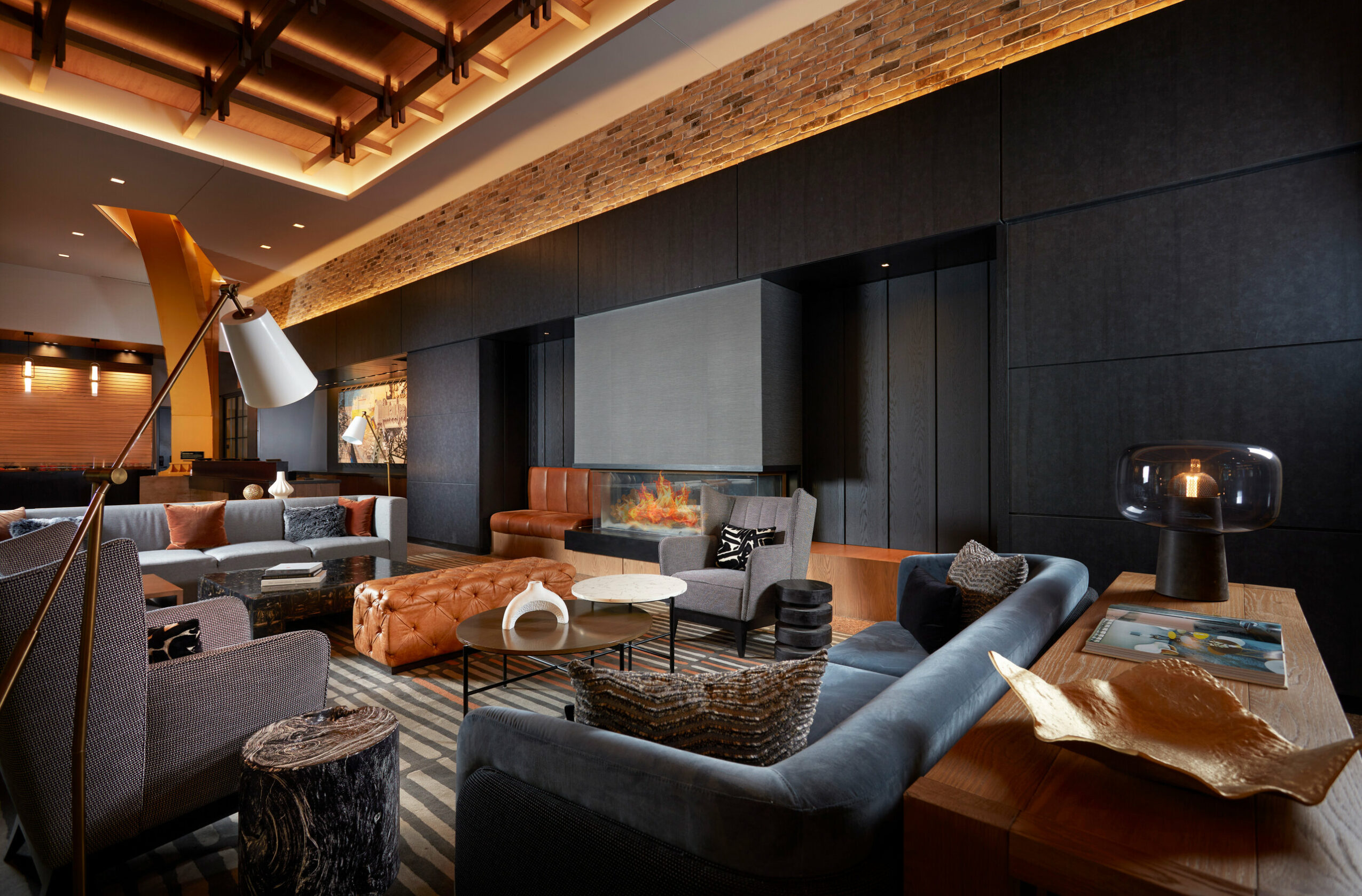 Modern lounge with sofas, armchairs, a fireplace, and decorative lighting in a stylish interior.