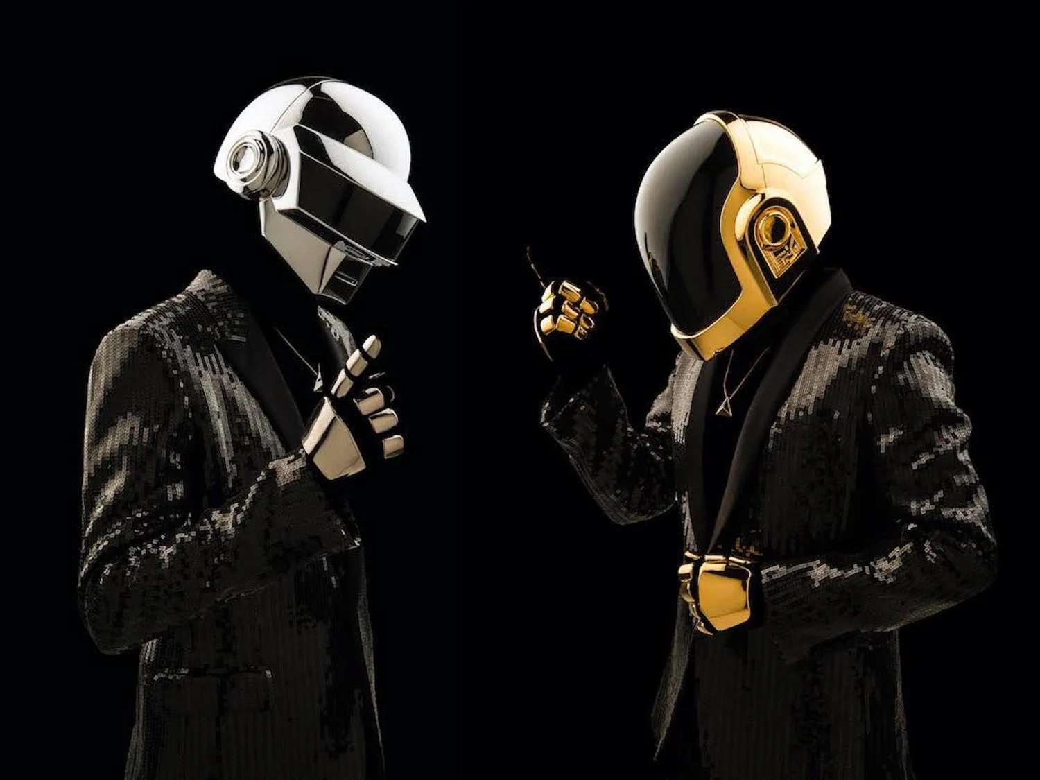 Two people in black suits wearing futuristic helmets, one white and one yellow, against a black background.