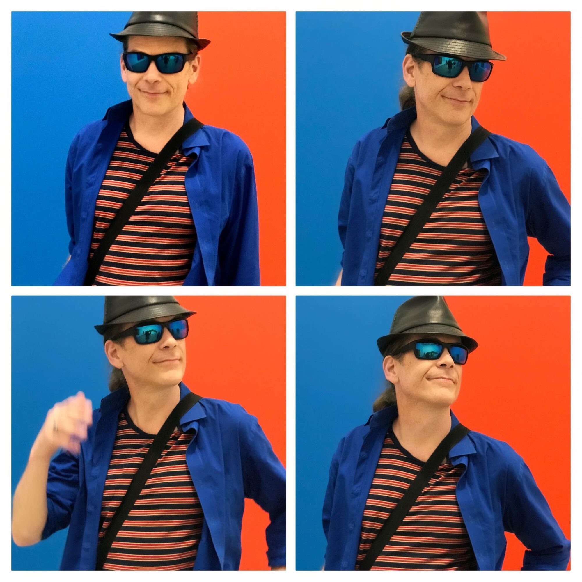 Woman wearing sunglasses, hat, striped shirt, and blue jacket against a red and blue background, smiling and posing.