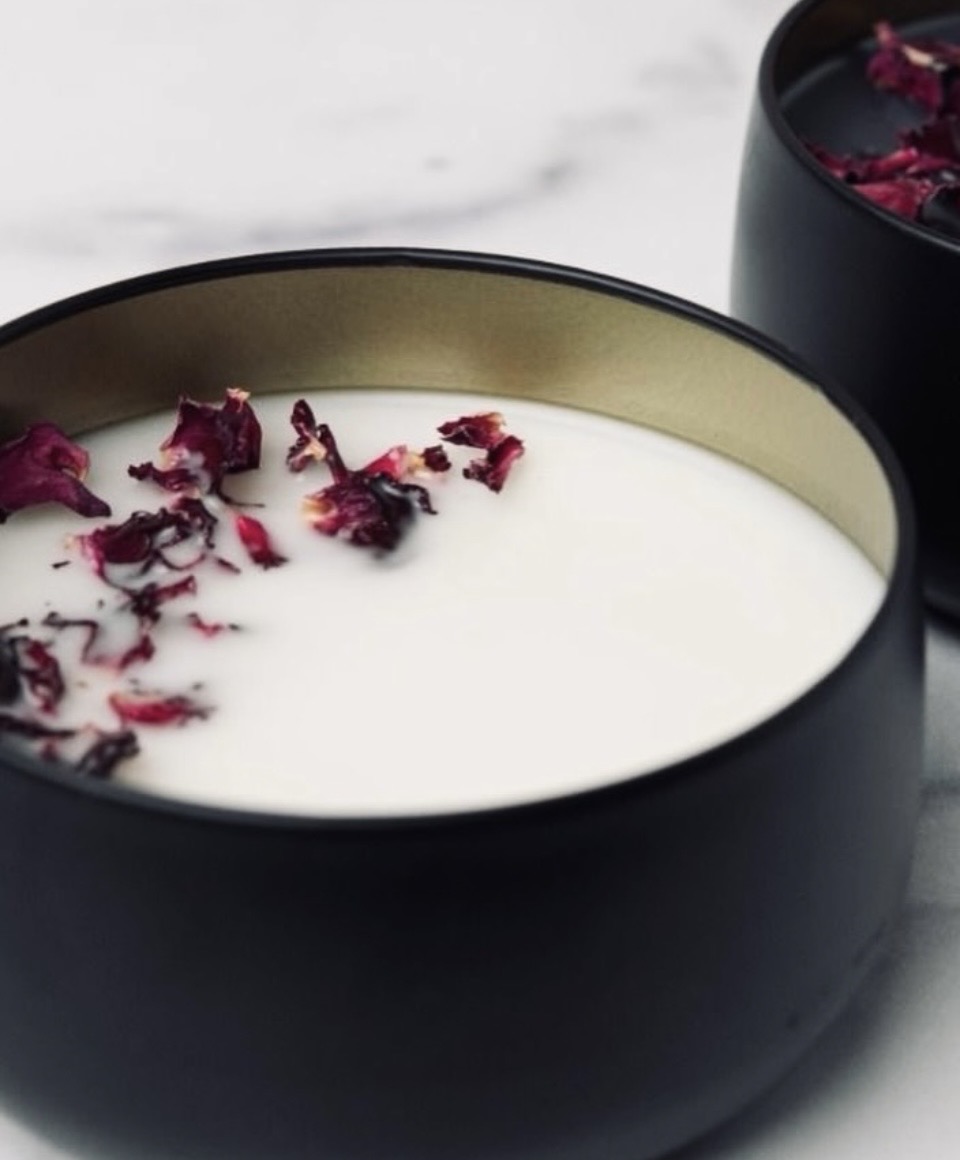 A black bowl with white liquid and dried rose petals on top, with another similar bowl partially visible in the background.