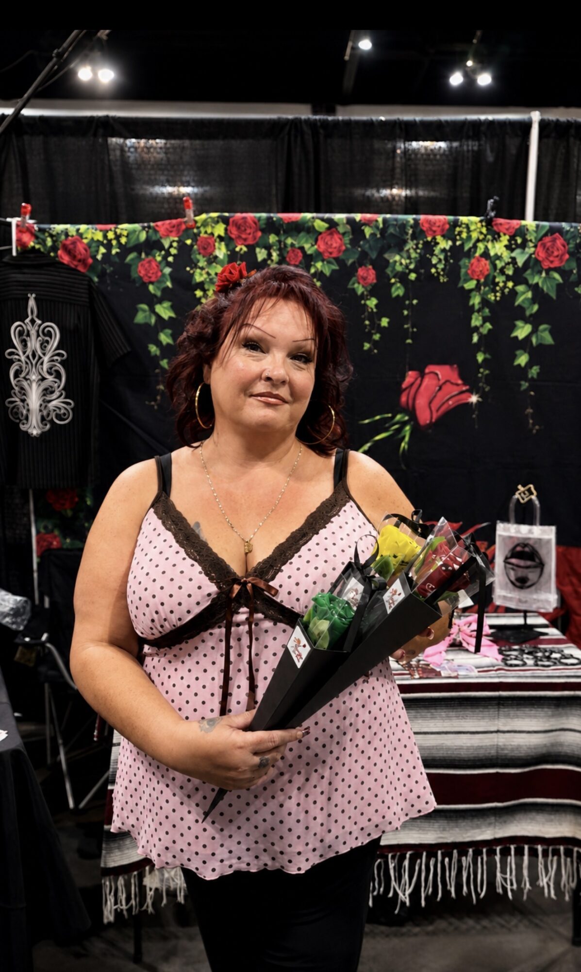 Woman holding a bouquet of flowers, standing in front of a display with clothing and decorative items.