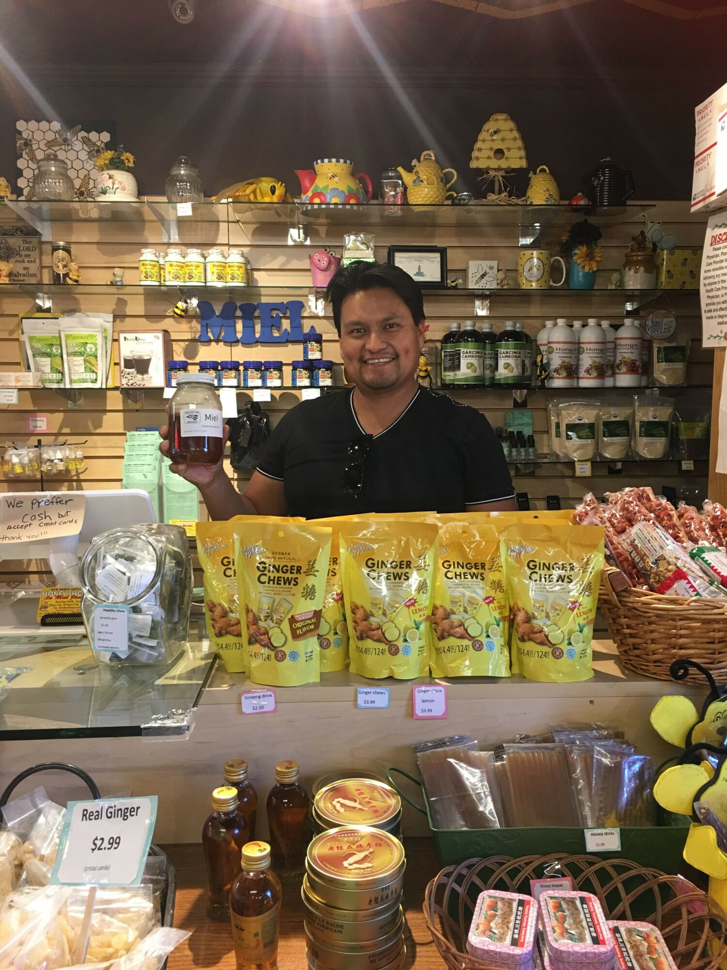 Person standing behind a counter with yellow snack bags, surrounded by various products and decorations.