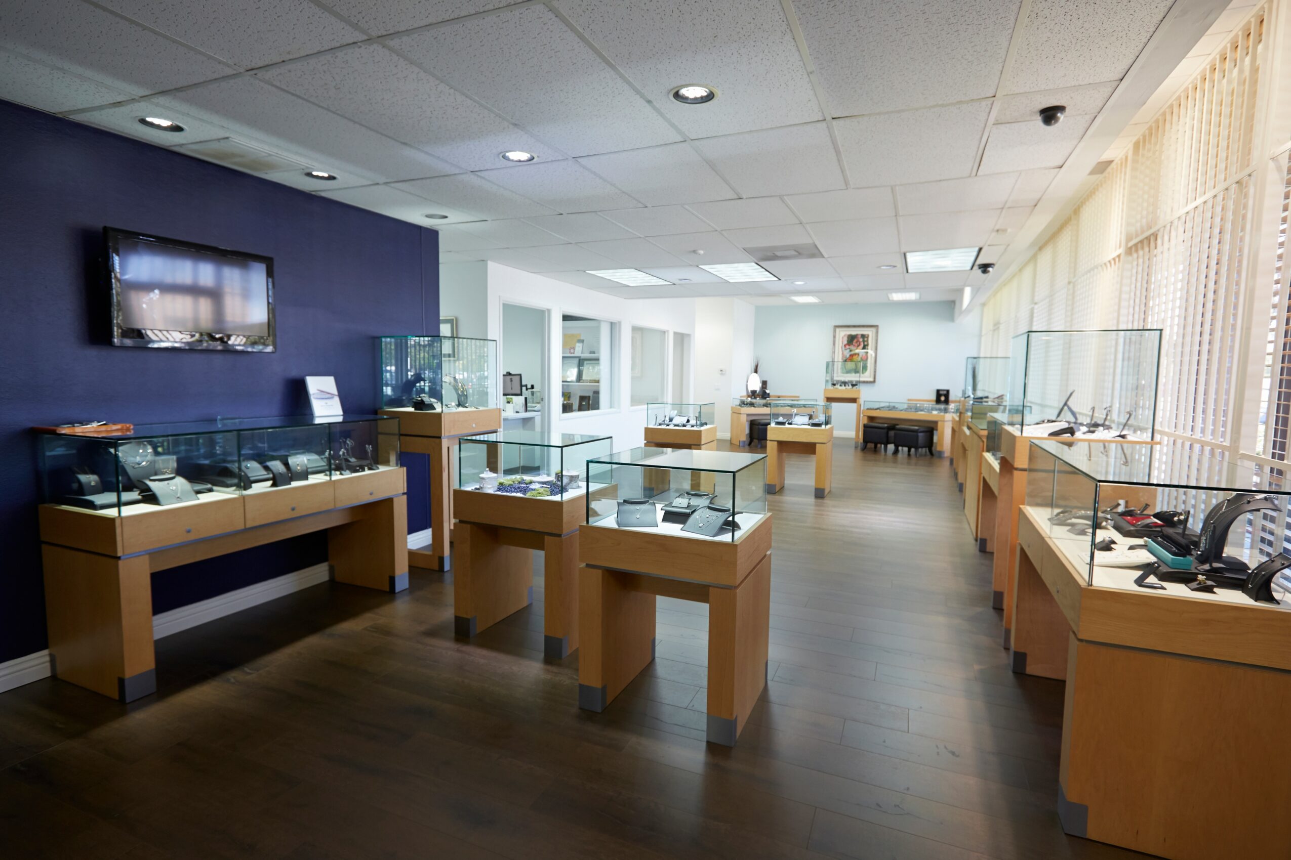 Museum exhibit room with display cases, a wall-mounted TV, and a seating area in the background.