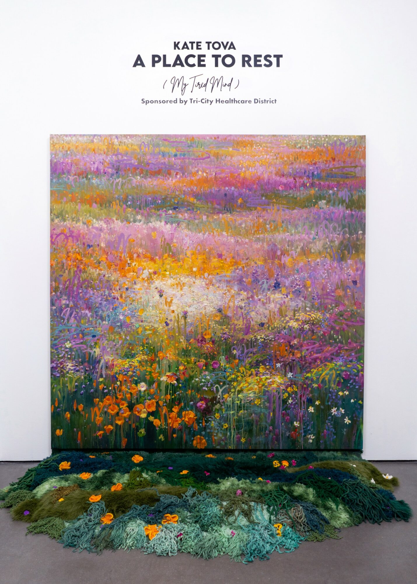 Colorful floral painting with a textured, green base at the bottom, titled 'A Place to Rest' by Kate Tova, sponsored by Tai City Healthcare District.