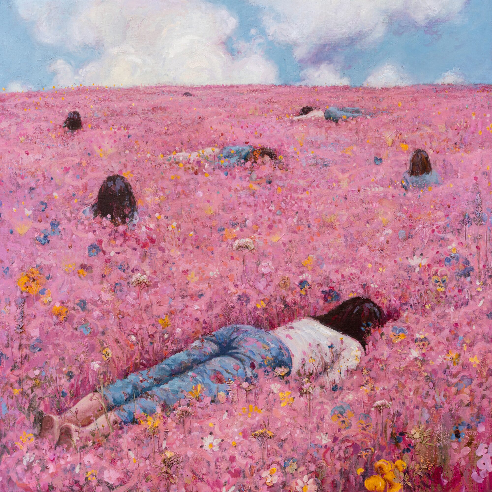 Person lying face down in a pink flower field with other people in the distance under a partly cloudy sky.