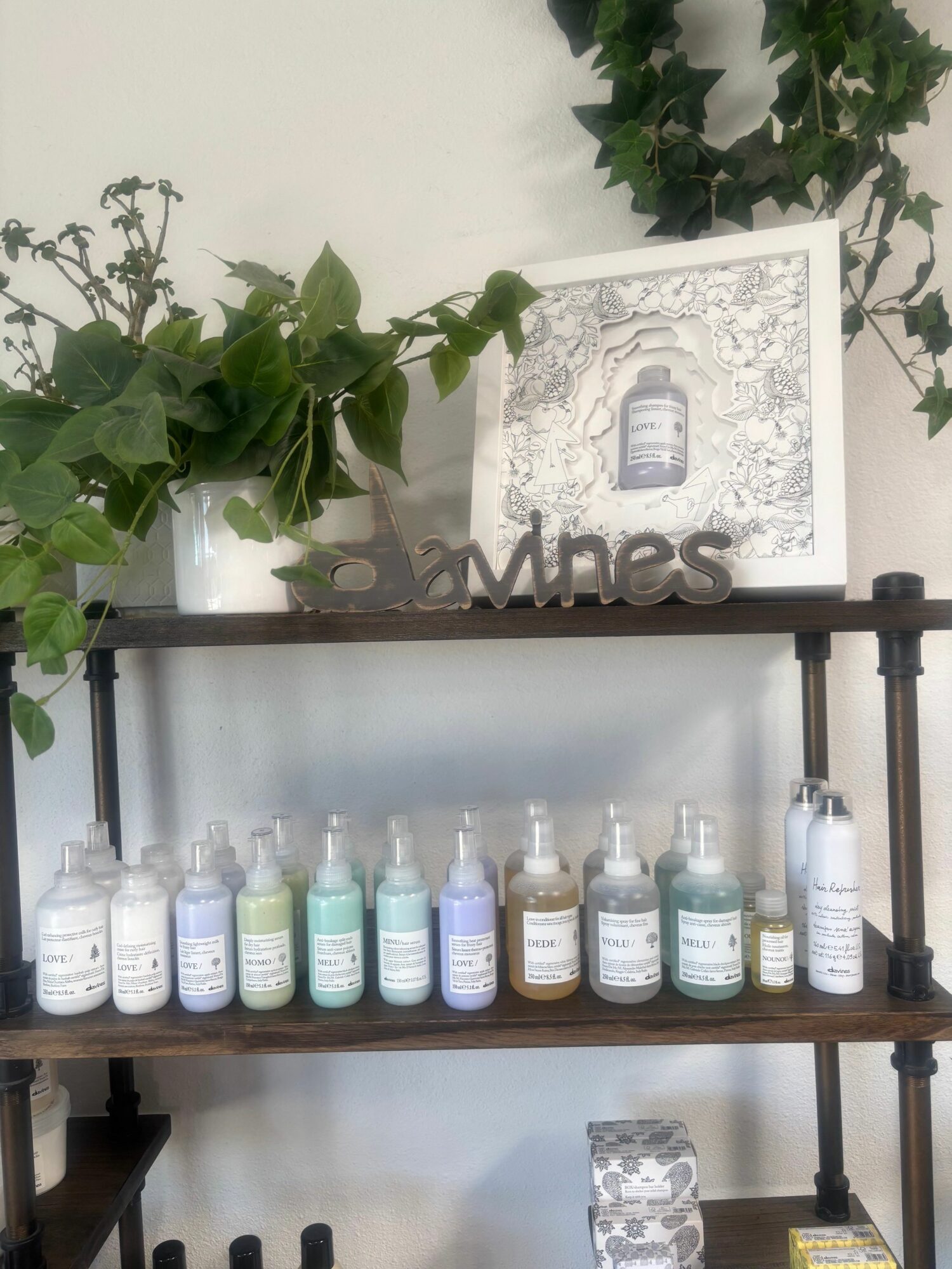 Display shelf with various bottles, a plant, and a framed picture, viewed sideways.