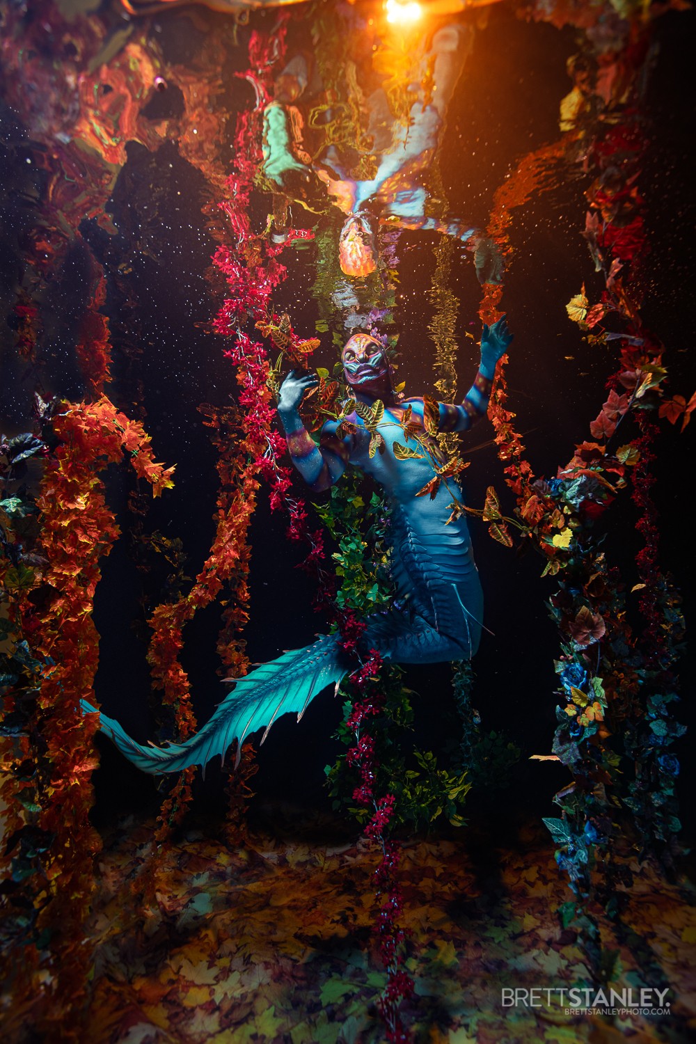Underwater scene with a blue mermaid surrounded by colorful coral and marine life.