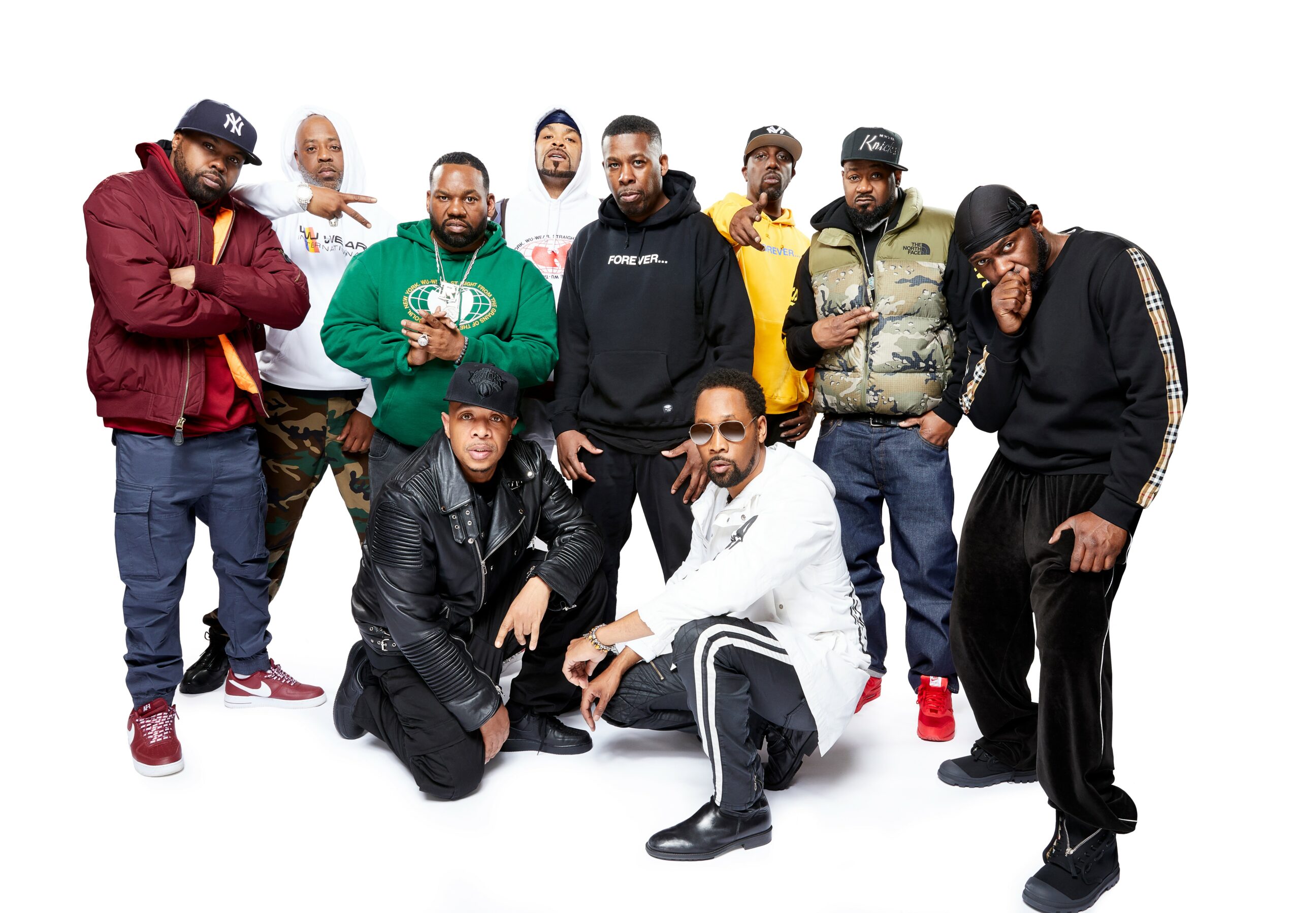 Group of ten men posing together, some standing and some kneeling, against a white background.