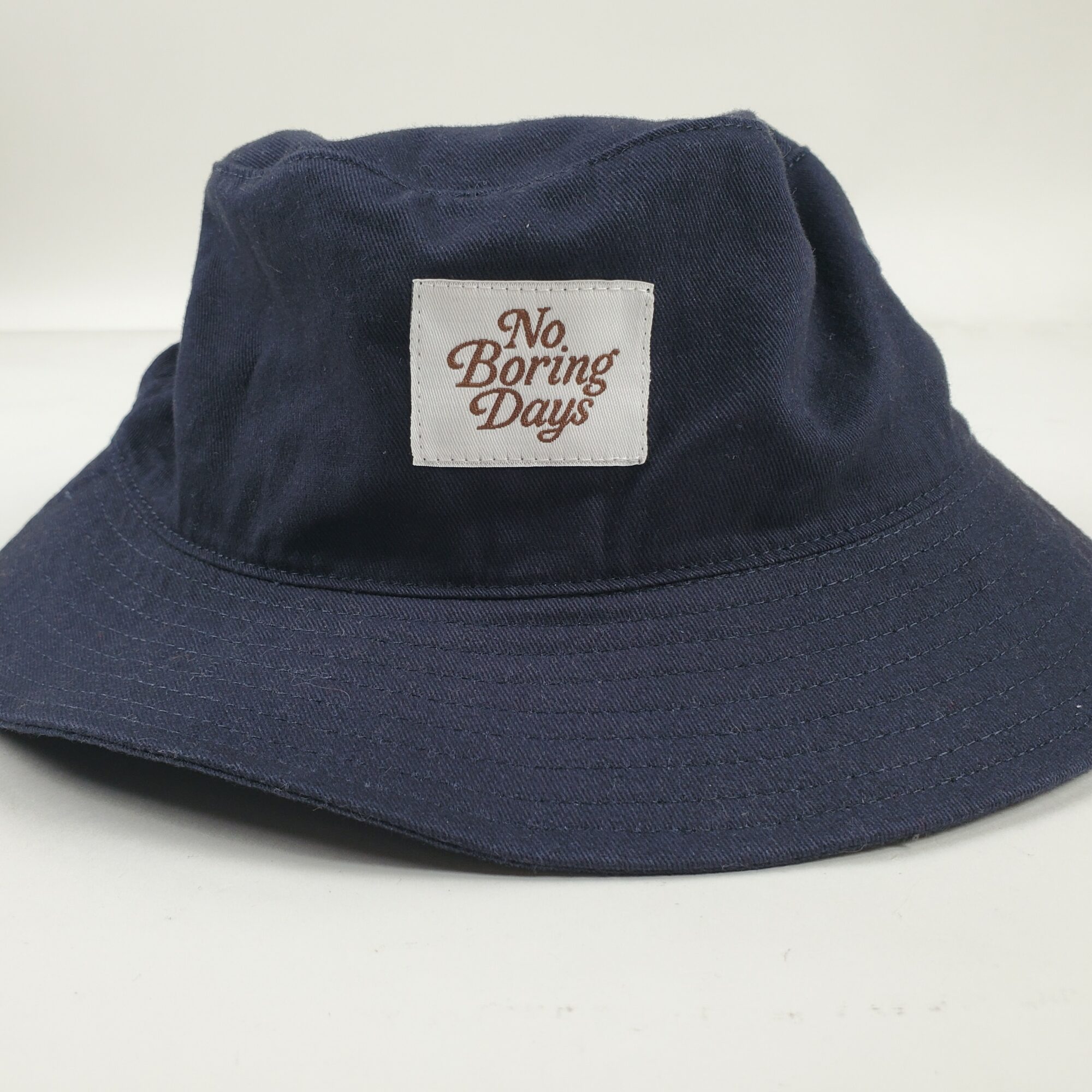 Dark blue bucket hat with a white patch reading 'No Boring Days' on the front.