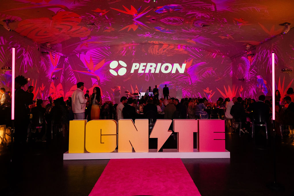 Event space with a large screen displaying 'PERION' and colorful lighting, with people and a pink carpet in front.