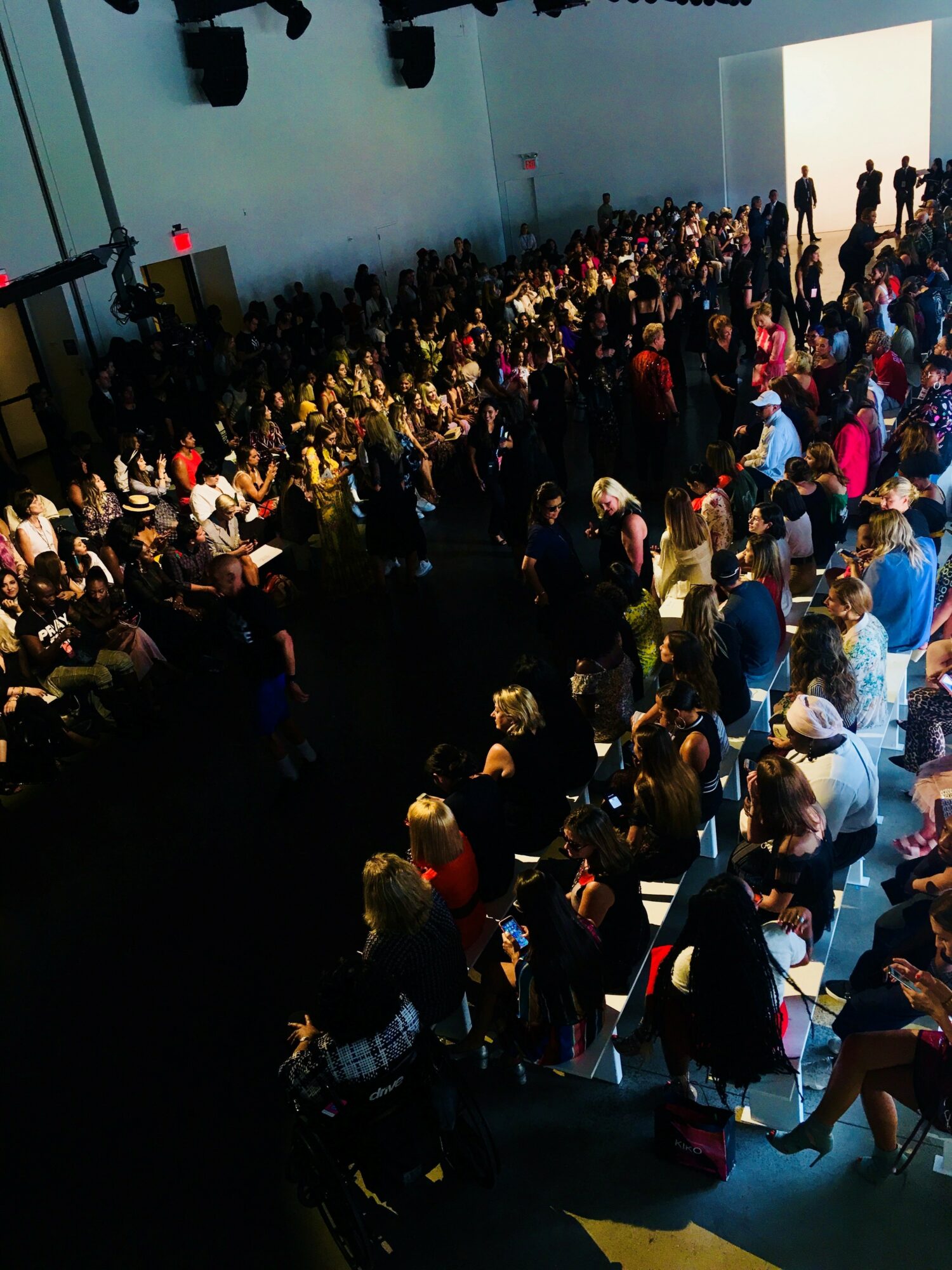 Large crowd of people gathered in an indoor space with a high ceiling and white walls.