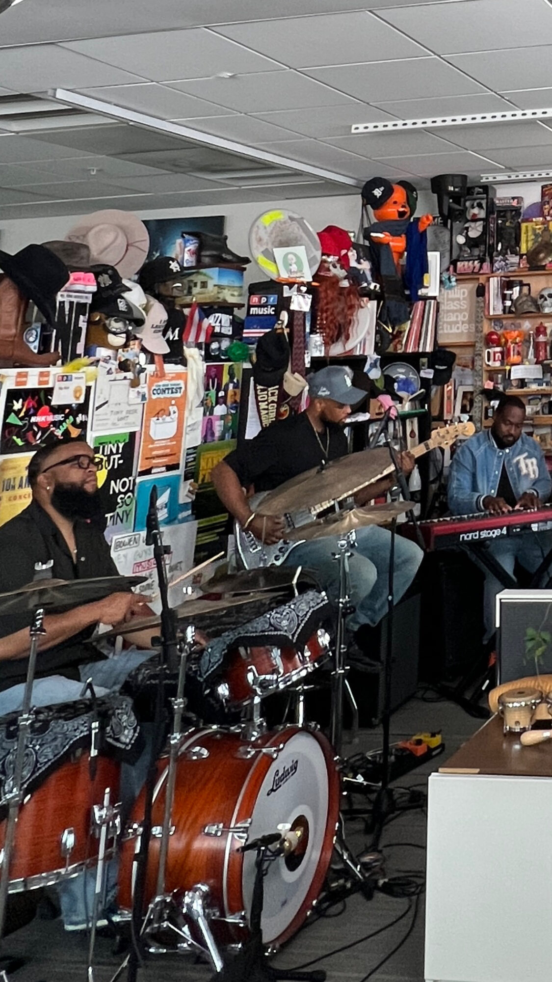 Three musicians playing instruments in a store with shelves of products behind them.