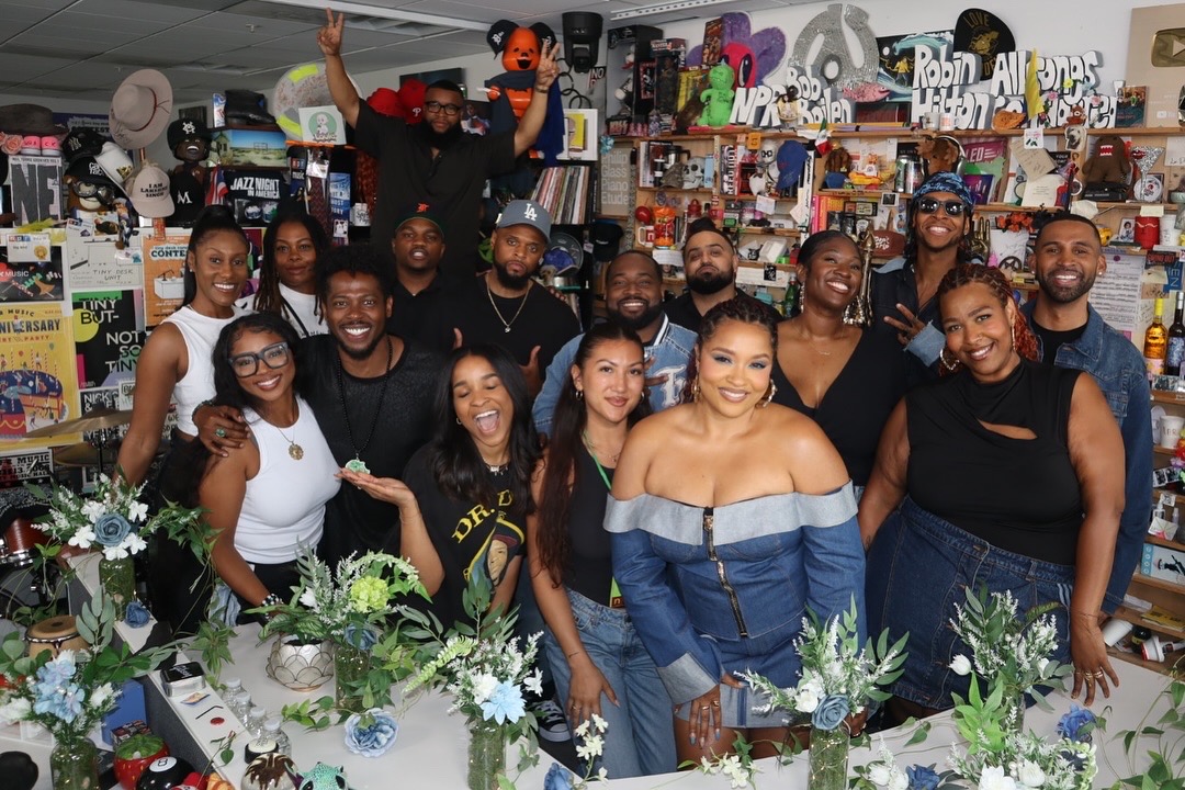 Group of people smiling and posing in a store with colorful decorations and plants on display.