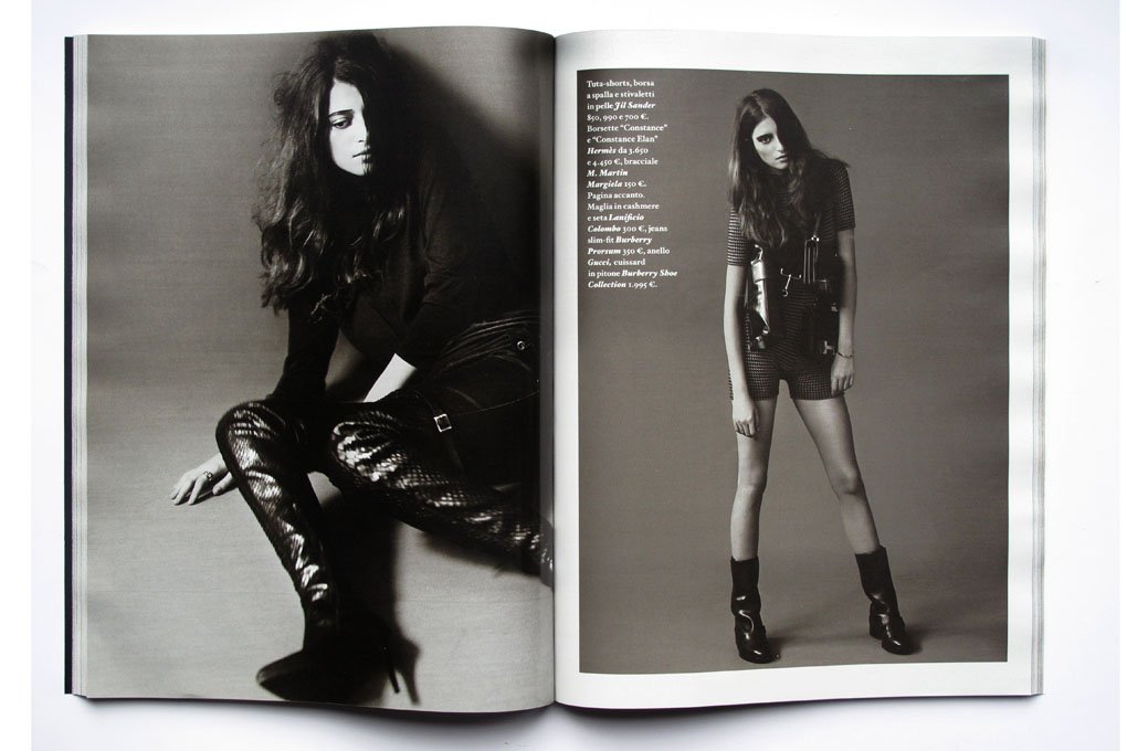 Two-page black and white fashion magazine spread featuring a woman with long hair in dark clothing, one sitting and one standing, with text on the right page.