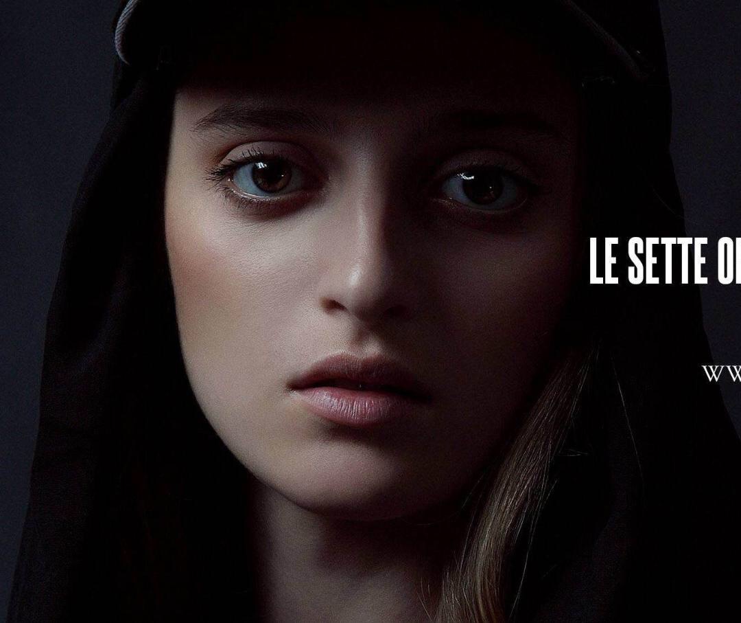 Close-up of a young woman's face with dark background, serious expression, and text partially visible on the right.