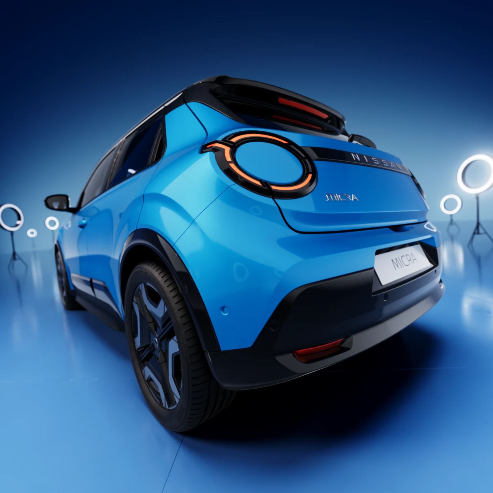 Blue compact electric vehicle displayed in a futuristic setting with glowing circles, viewed from the rear side, with a clear sky background.