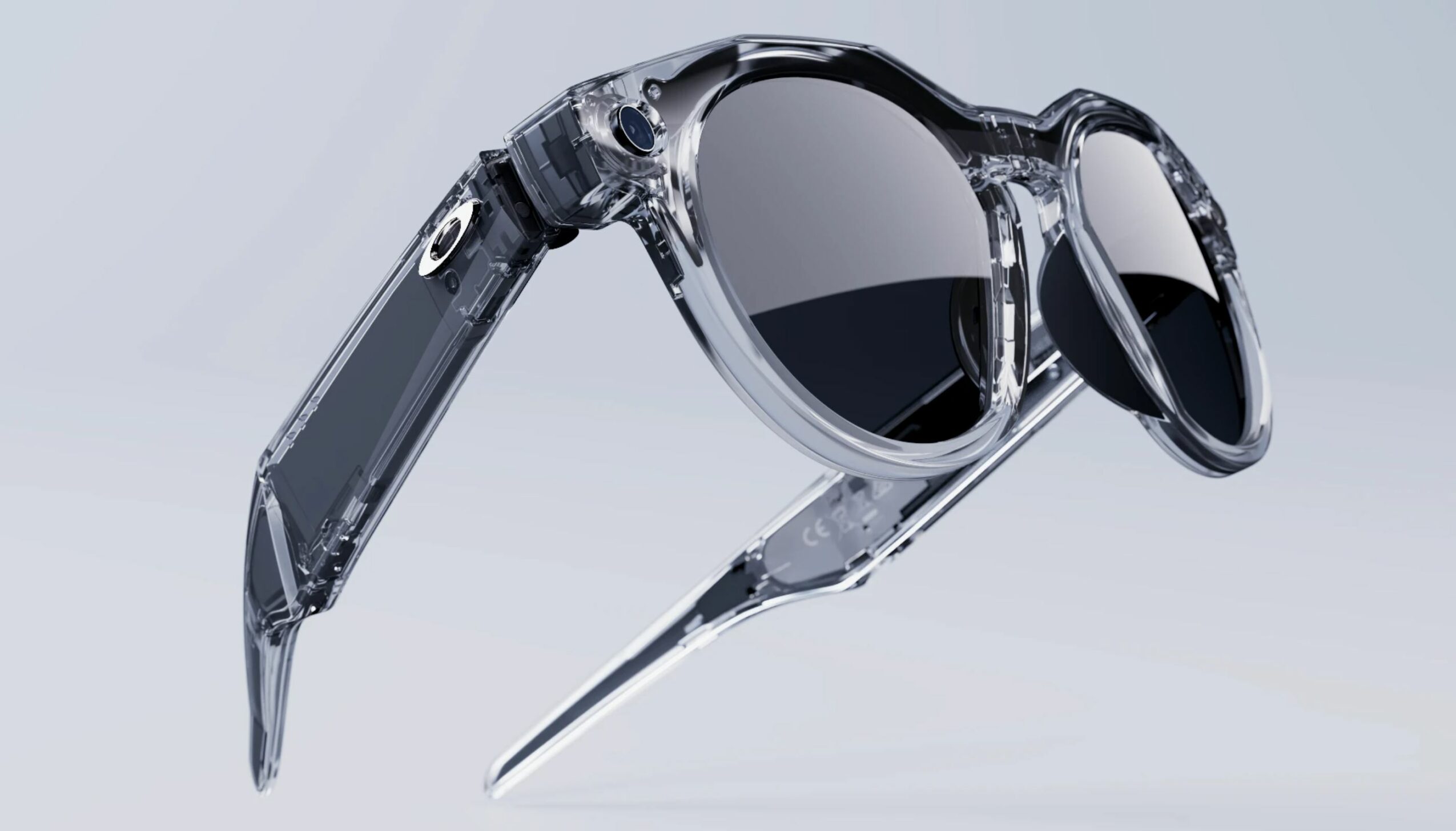 Pair of sunglasses with transparent frame and dark lenses, angled against a light background.