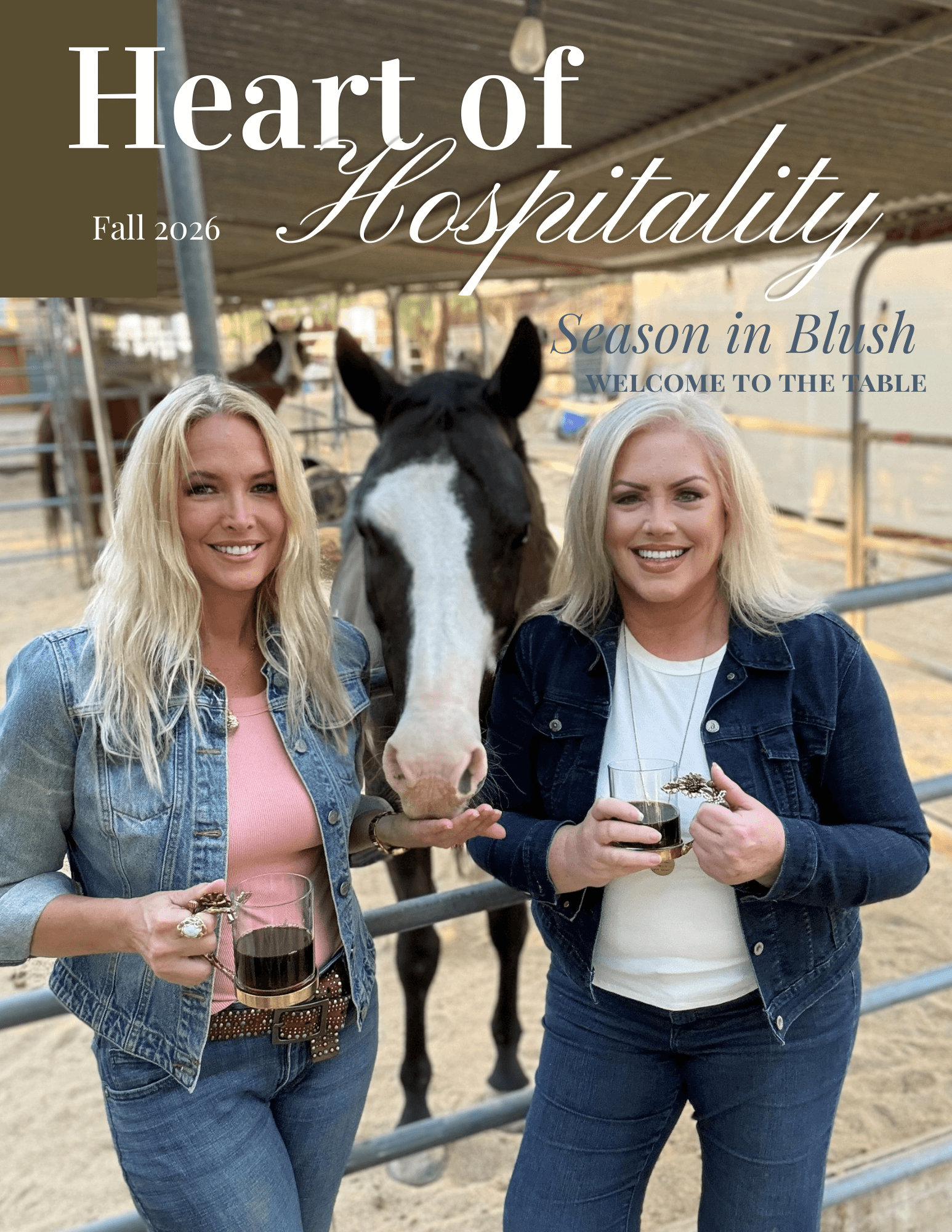 Two women with blonde hair smiling and holding drinks, standing next to a horse in a stable.