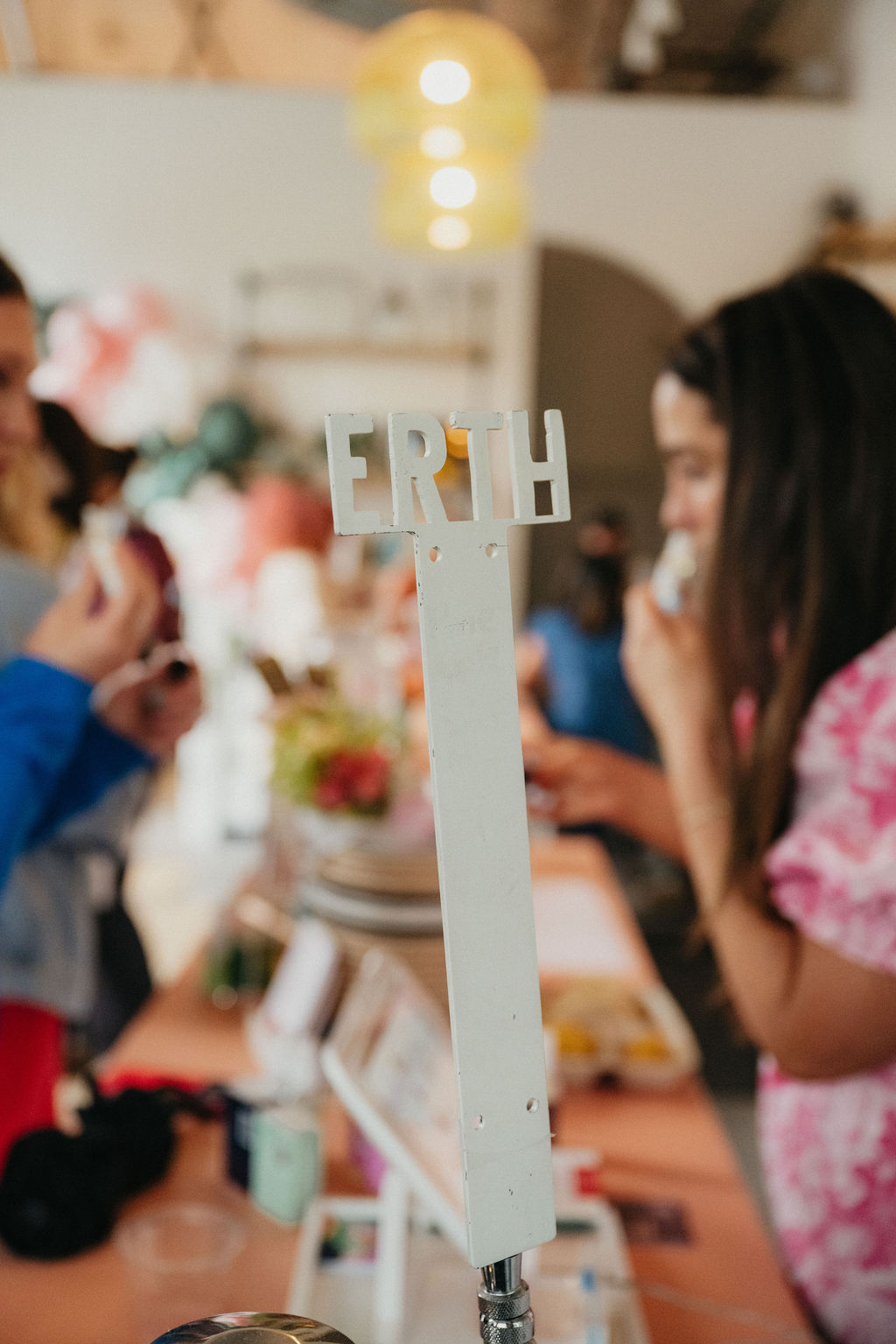Table with a white sign reading 'ER' in a lively indoor gathering, blurred people in background, warm lighting.