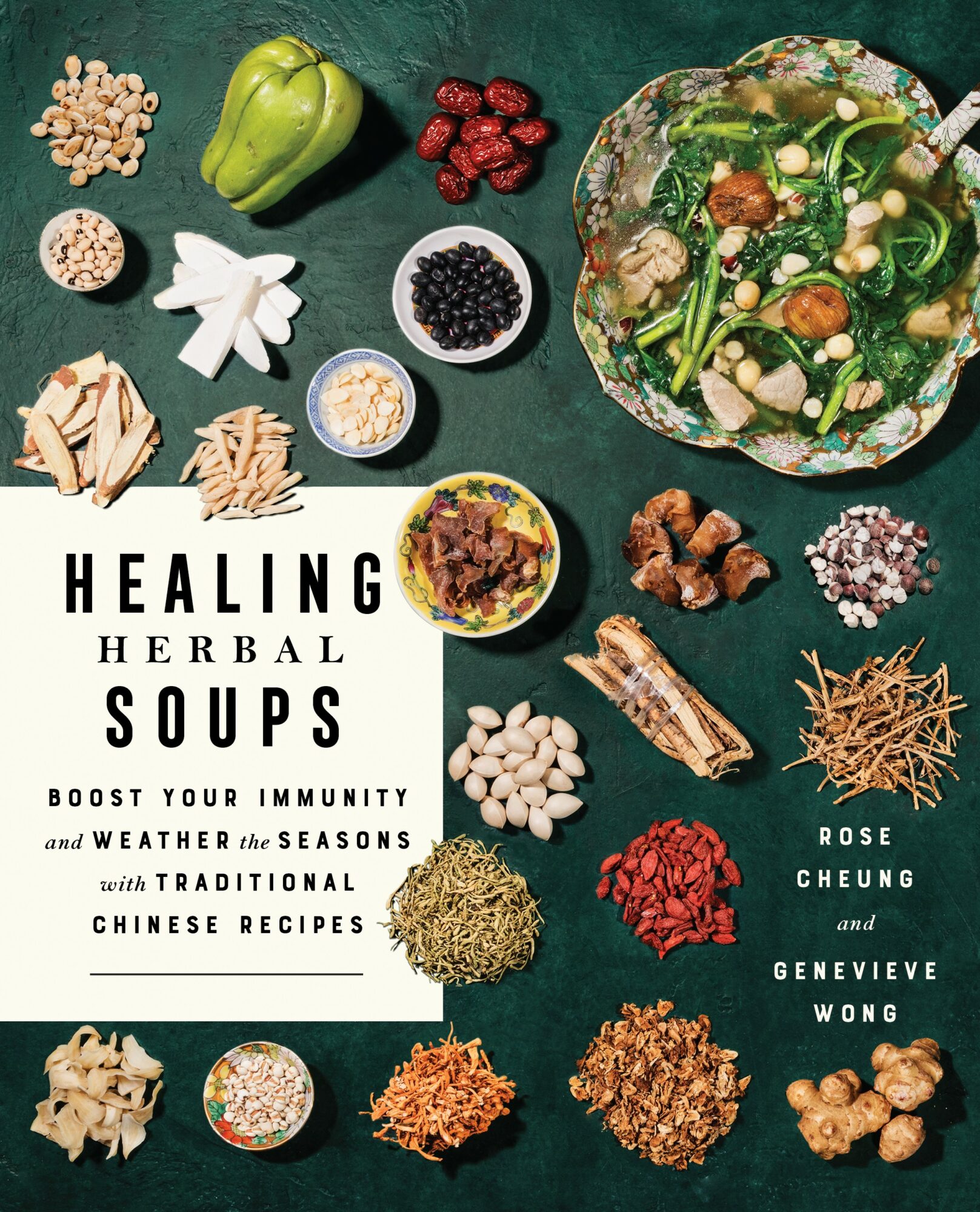 Book cover titled 'Healing Herbal Soups' with various herbs, vegetables, and ingredients arranged on a green surface.
