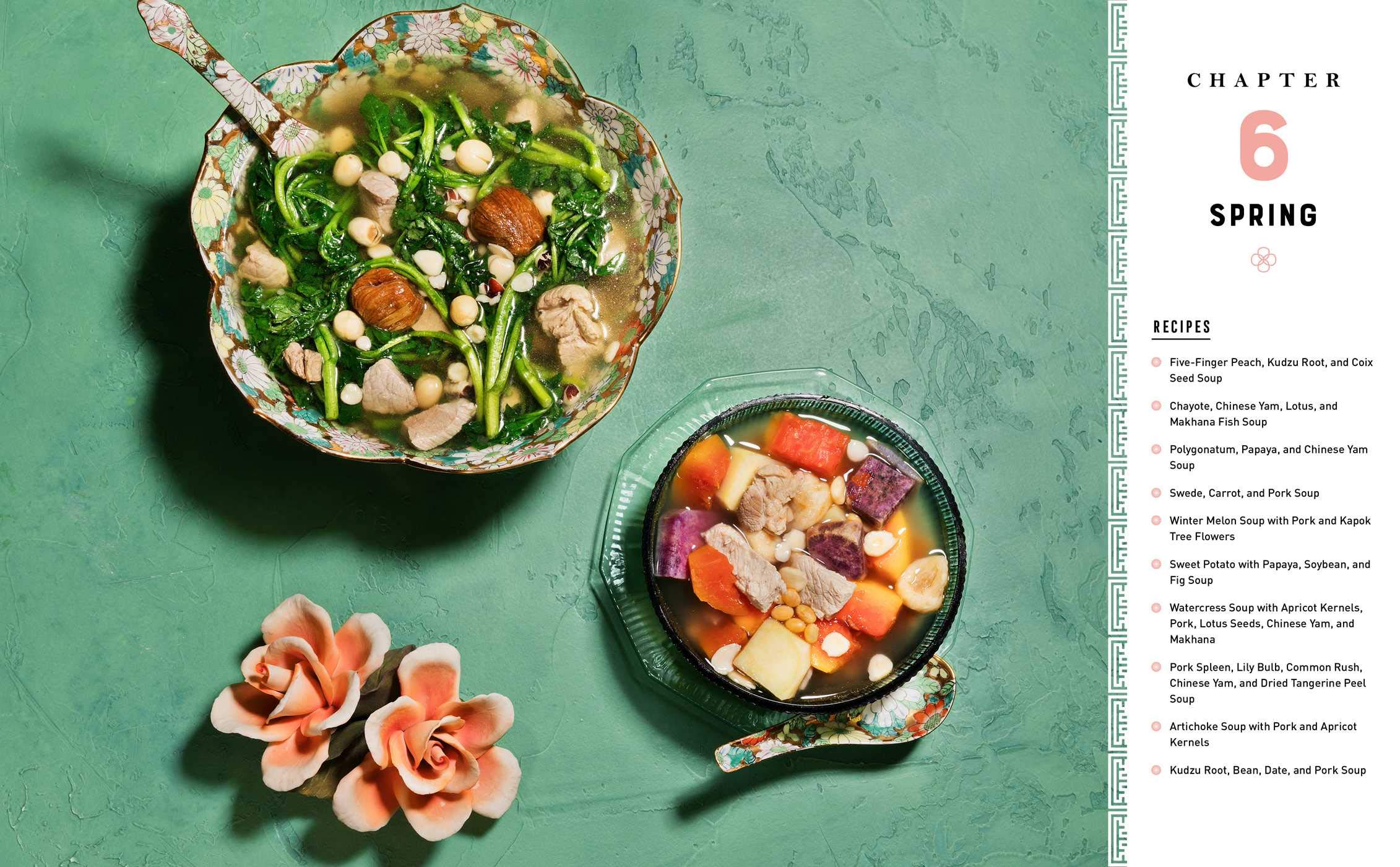 Two bowls of salad and soup on a green surface with pink flowers, and a page from a magazine or book on the right side.