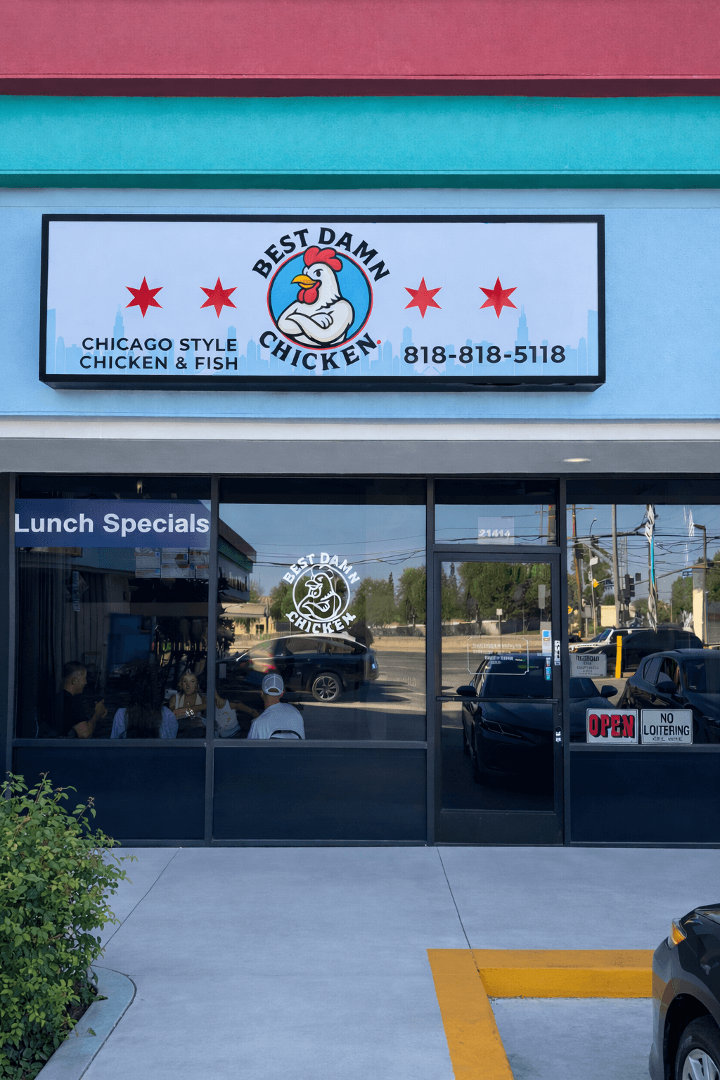 Storefront with a sign for Chicago Style Chicken & Fish, featuring a duck logo and phone number, glass doors, and a parking lot.