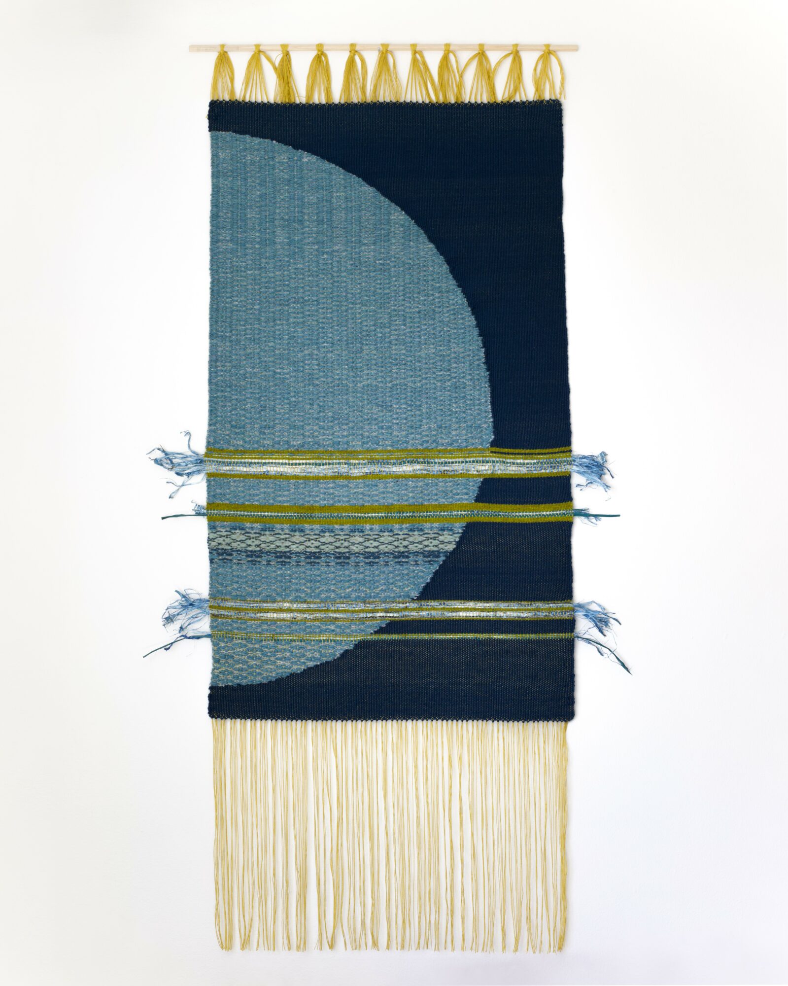 Decorative textile hanging with blue and dark blue sections, gold loops at top, fringes at bottom, and horizontal stripes.