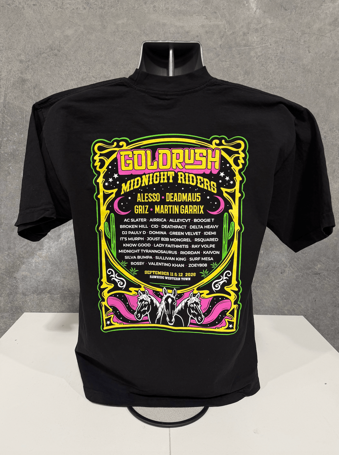 Black shirt with colorful graphic design and text, displayed on a mannequin against a gray background.