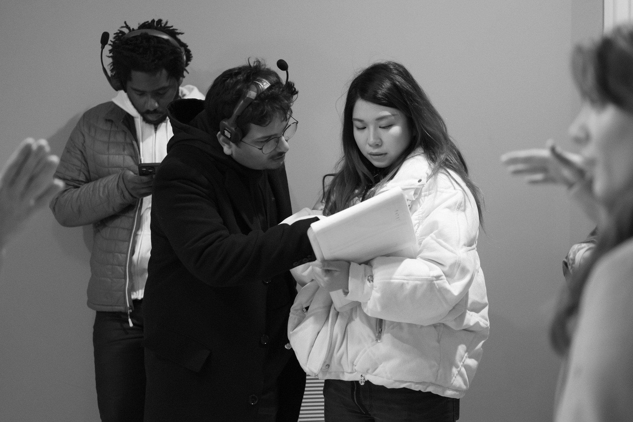Group of people in a discussion, with one person holding a notebook, in black and white.