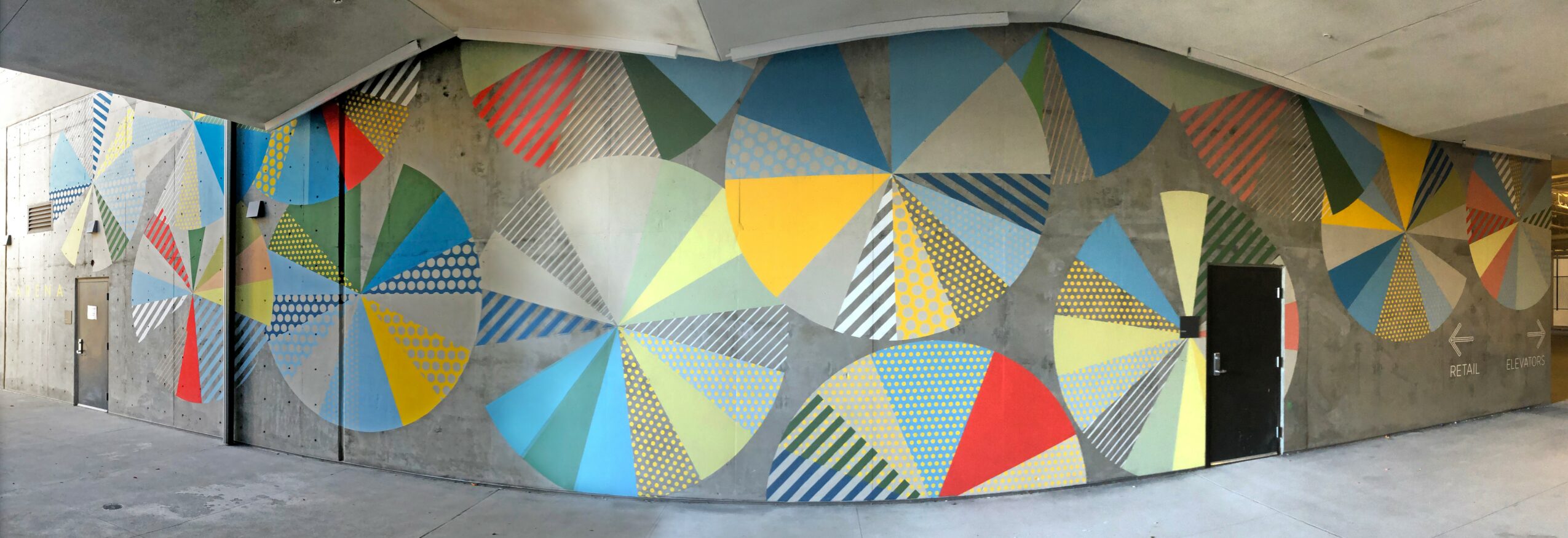 Colorful geometric mural with circles and triangles on a wall, with a door on the right side.