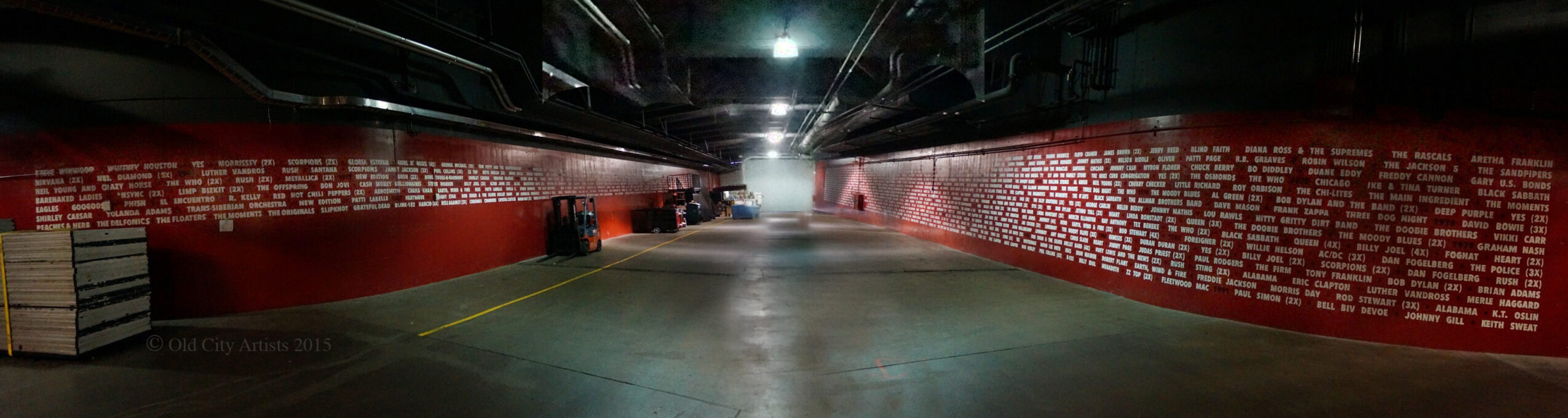 Empty indoor sports arena with red and white walls, empty floor, and bright overhead lights.