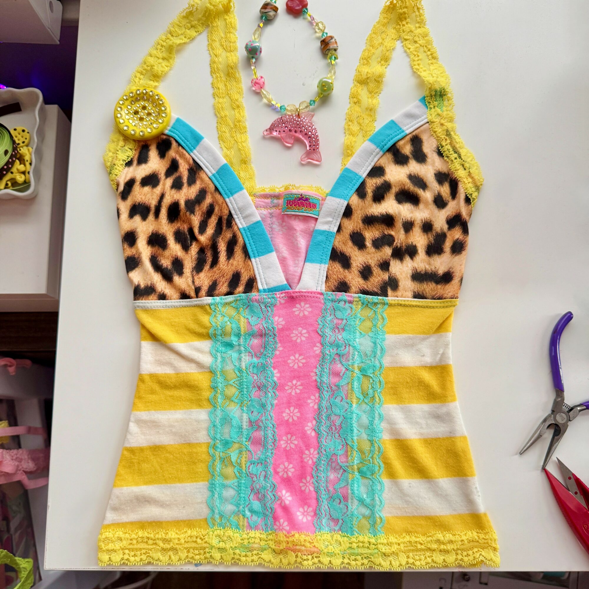 Colorful, patterned dress with yellow, pink, blue, and animal print elements, laid flat on a surface.
