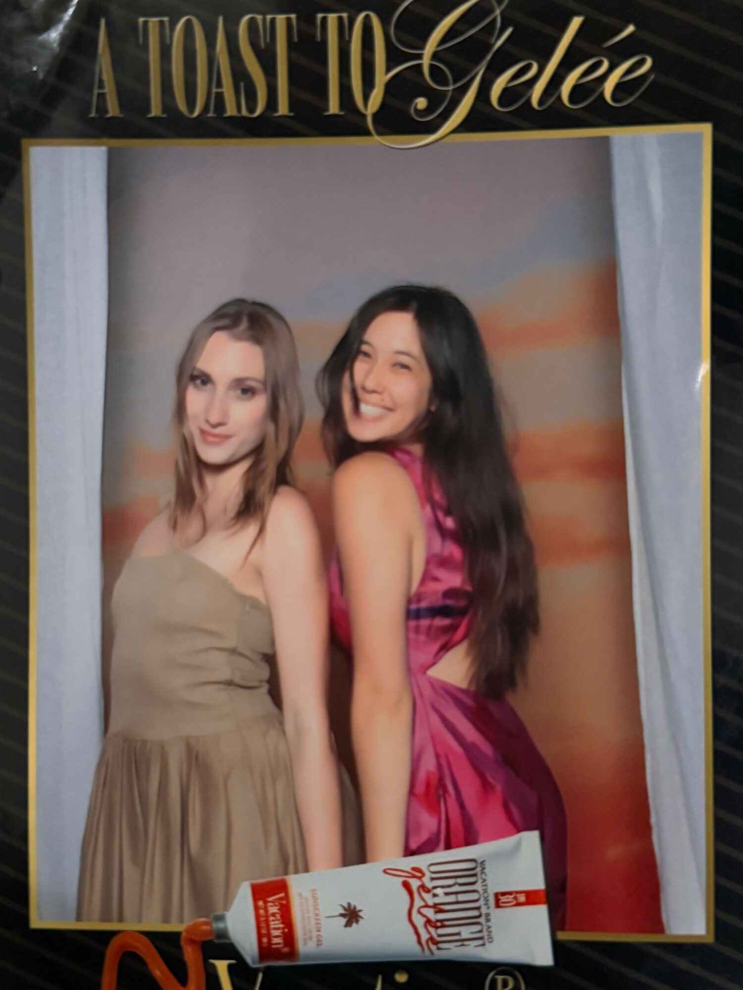 Two women in elegant dresses smiling, with a tube of gel in front, and a decorative frame with text.