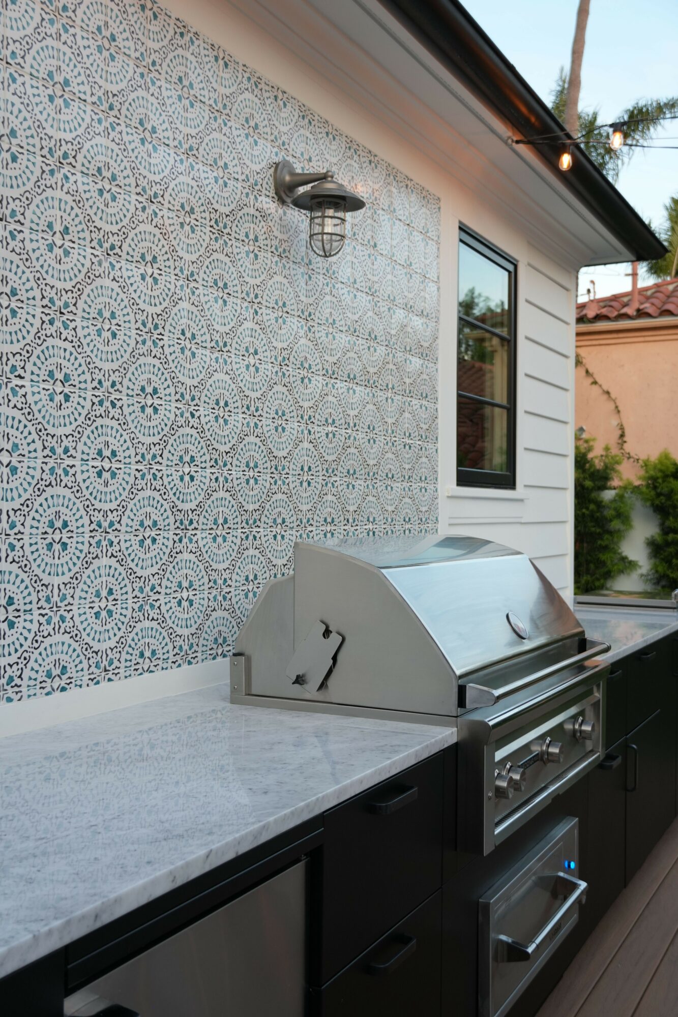 Kitchen counter with a white patterned backsplash, a window, and a white bread box, viewed from the side.