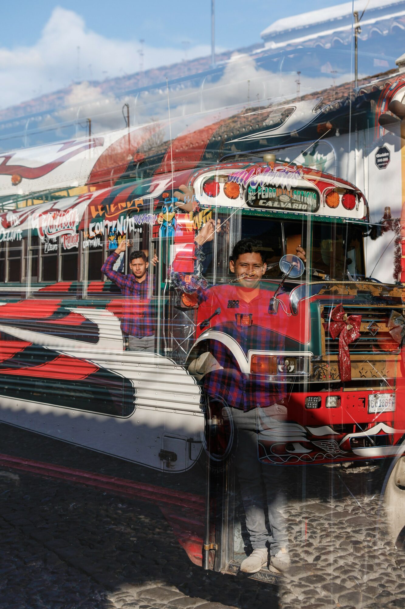 Children riding a colorful amusement park train with a decorative front, outdoors on a sunny day.