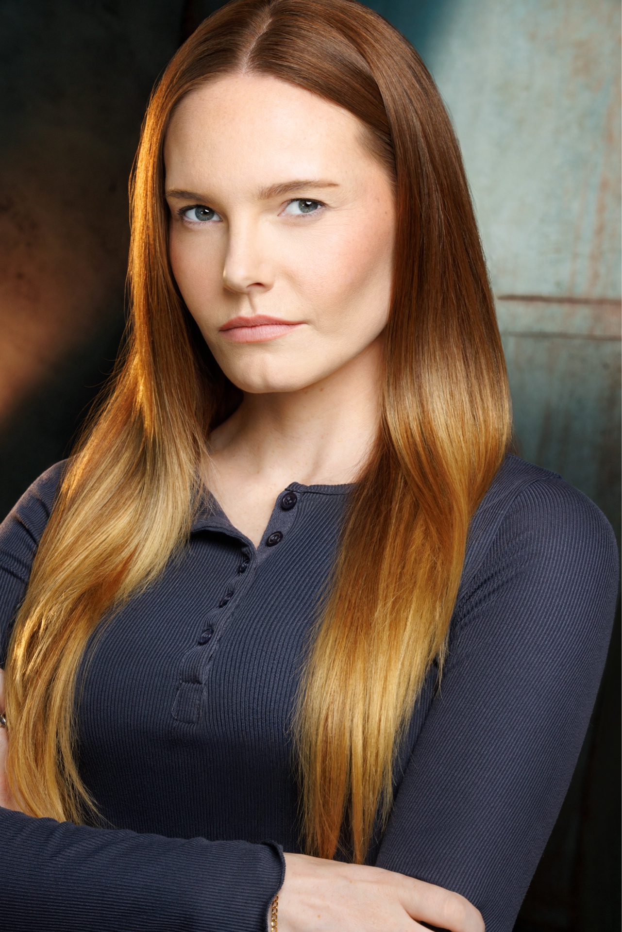 Woman with long, straight, reddish-brown hair, wearing a dark blue top, looking directly at the camera.