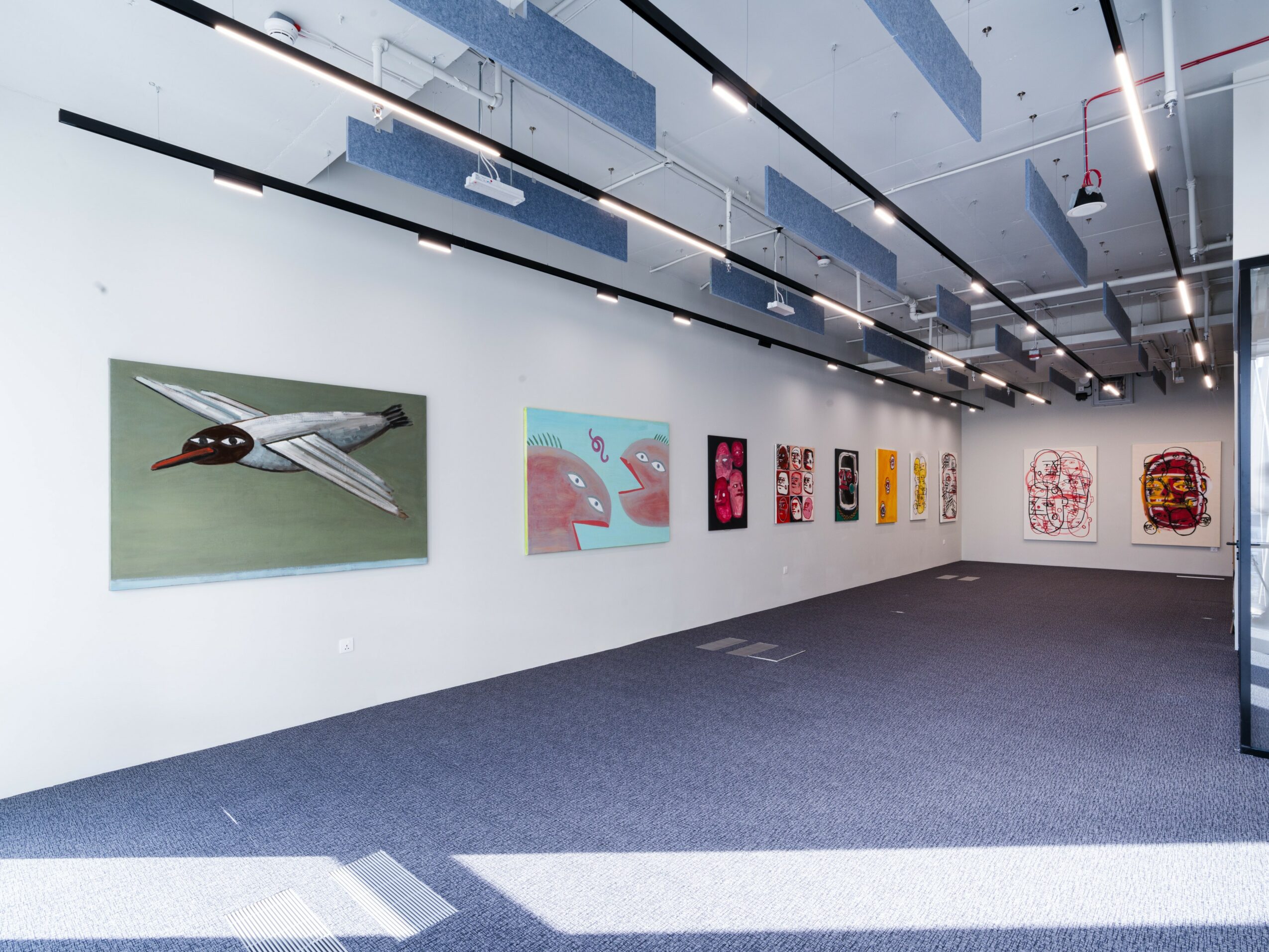 Gallery wall with colorful abstract and patterned artworks displayed in a modern, well-lit space.