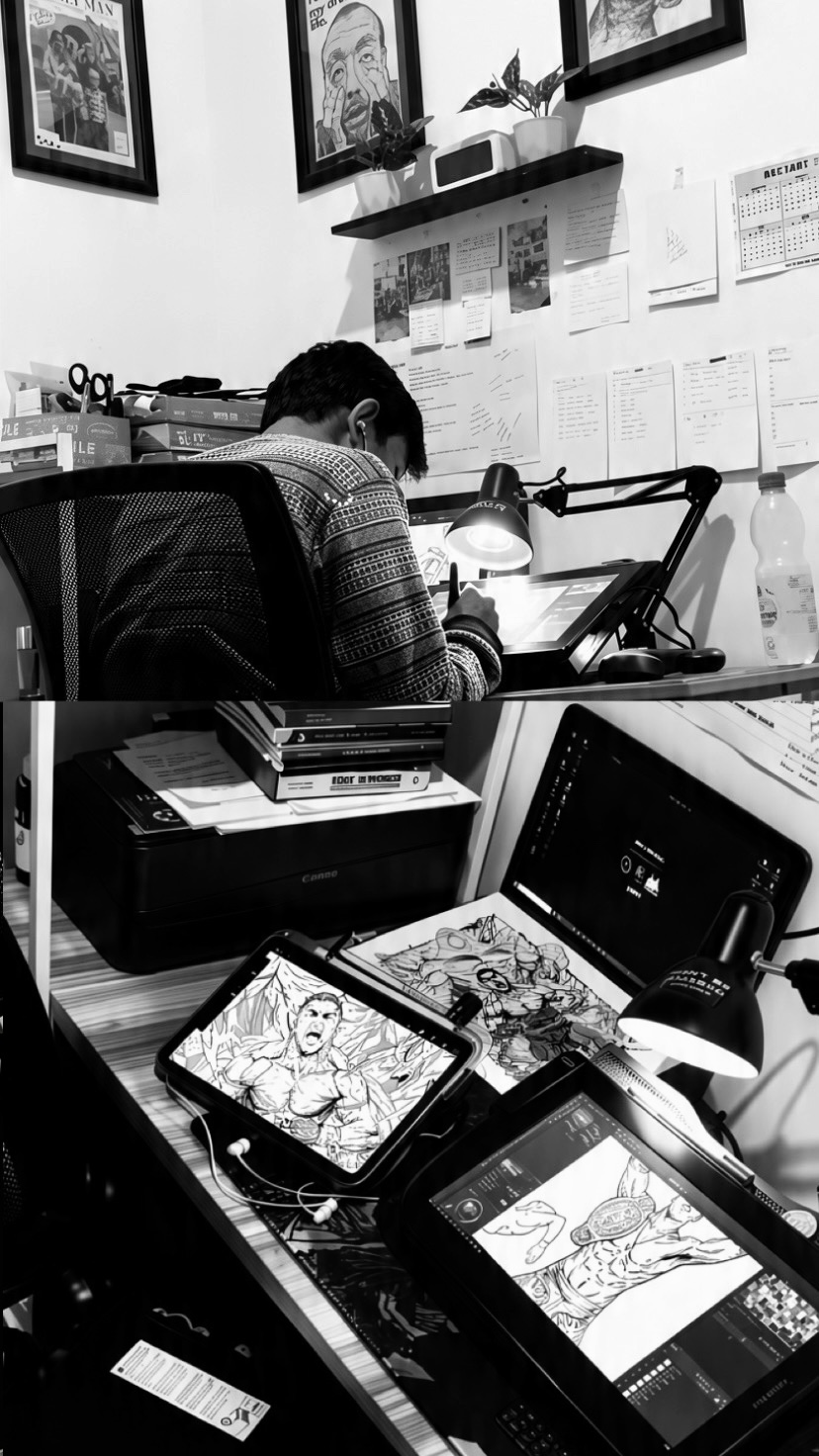 Person working at desk with multiple screens and papers, wall with framed pictures and notes, black and white image.