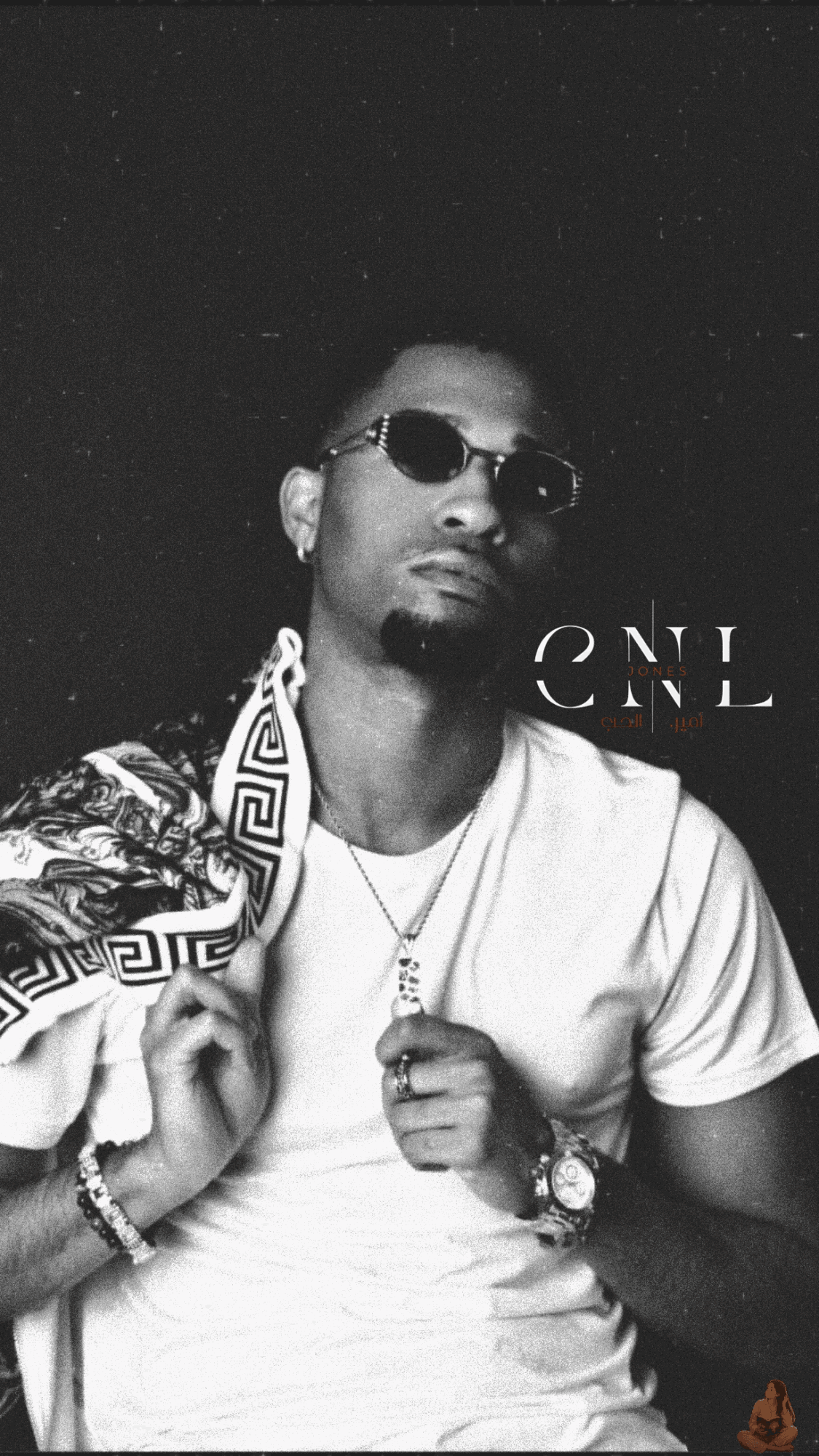 Man wearing sunglasses and a patterned jacket over a white T-shirt, holding a chain, against a dark background.