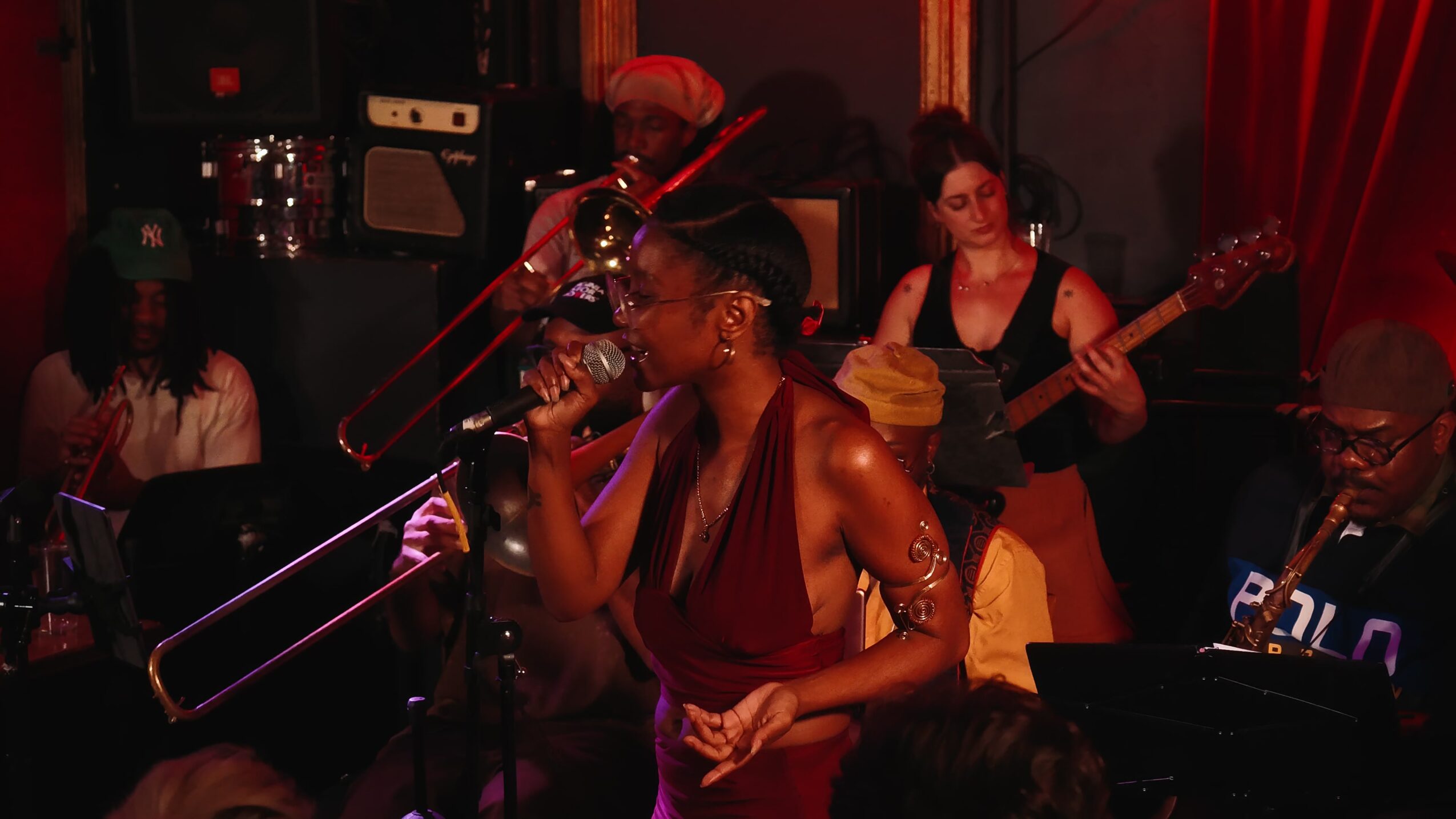 A woman singing into a microphone on stage with musicians playing instruments in the background.