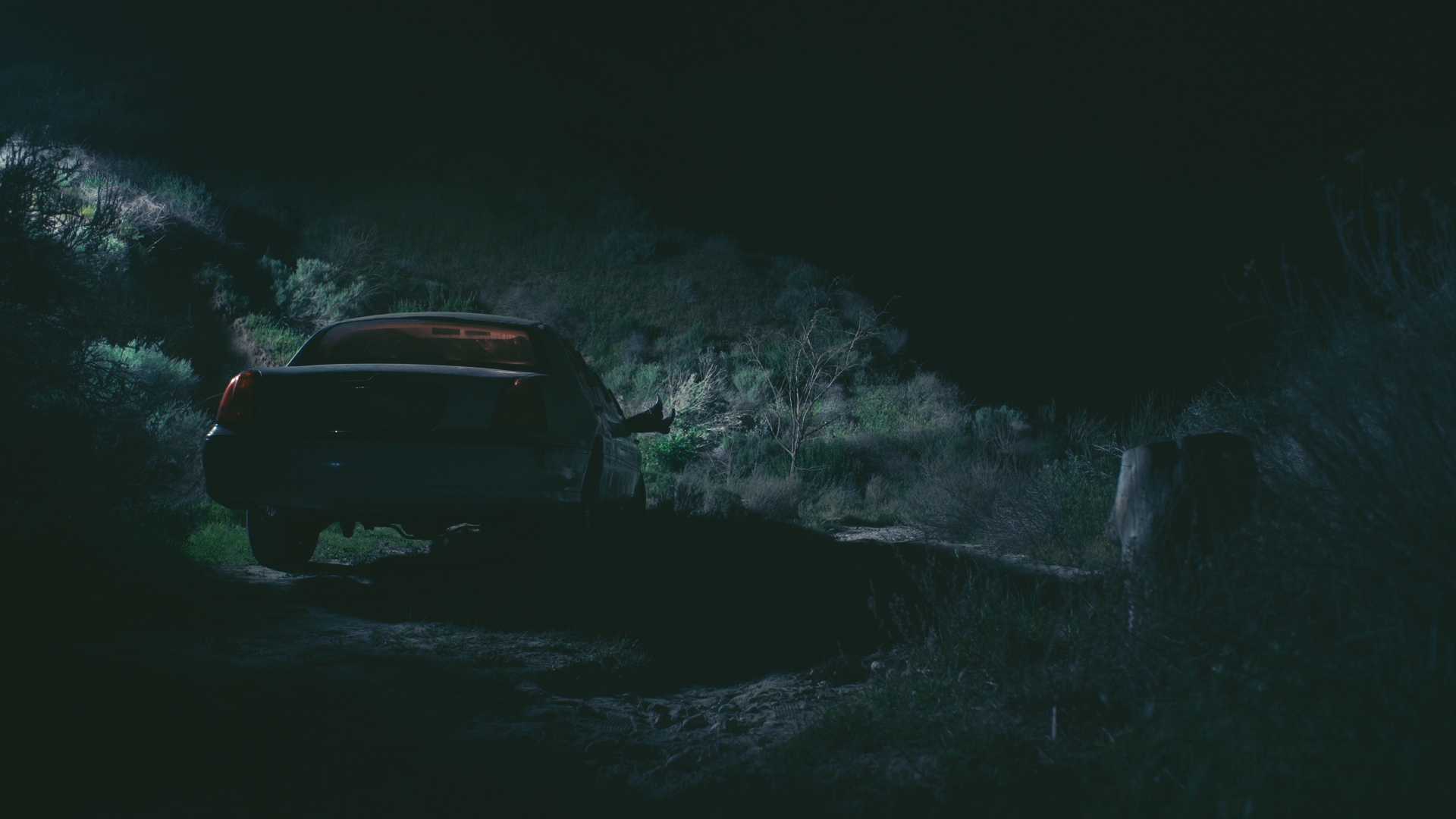 Car driving through water at night with splashes and dark surroundings.