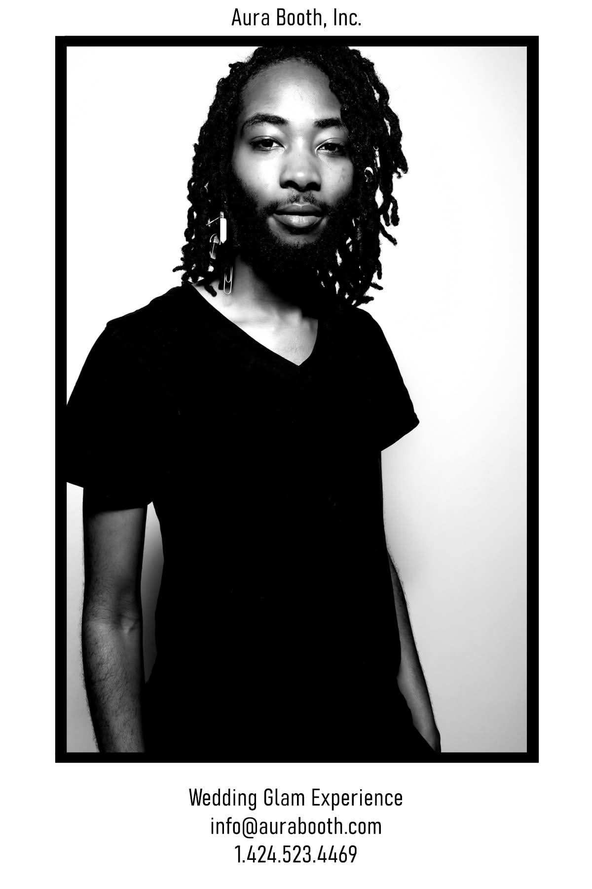 Portrait of a person with shoulder-length curly hair, wearing a black shirt, looking at the camera, black and white image.