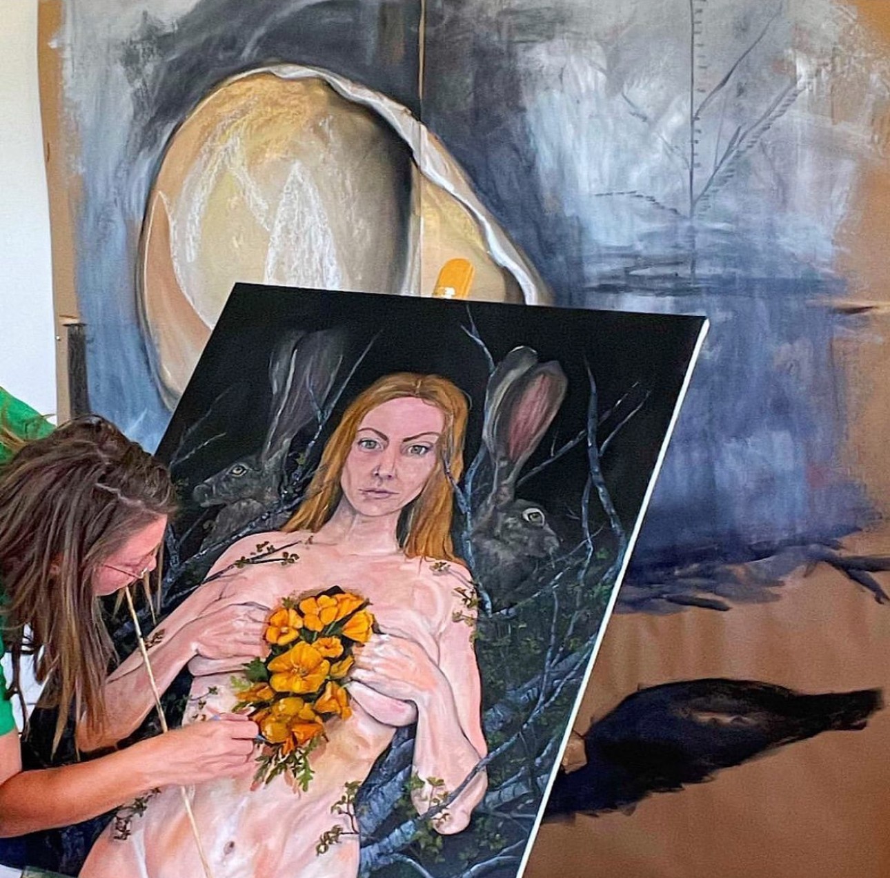 Artist working on a painting of a woman holding a bouquet of yellow flowers, with abstract background elements.