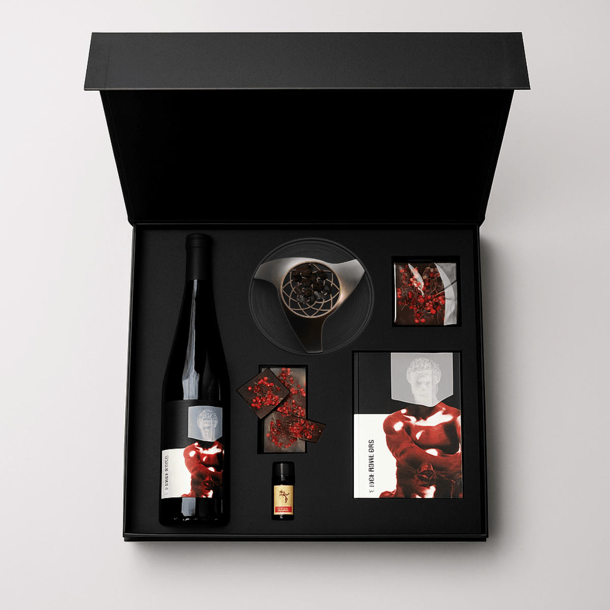 Open black box containing a wine bottle, a glass, a small bottle, and various cards and decorative items.