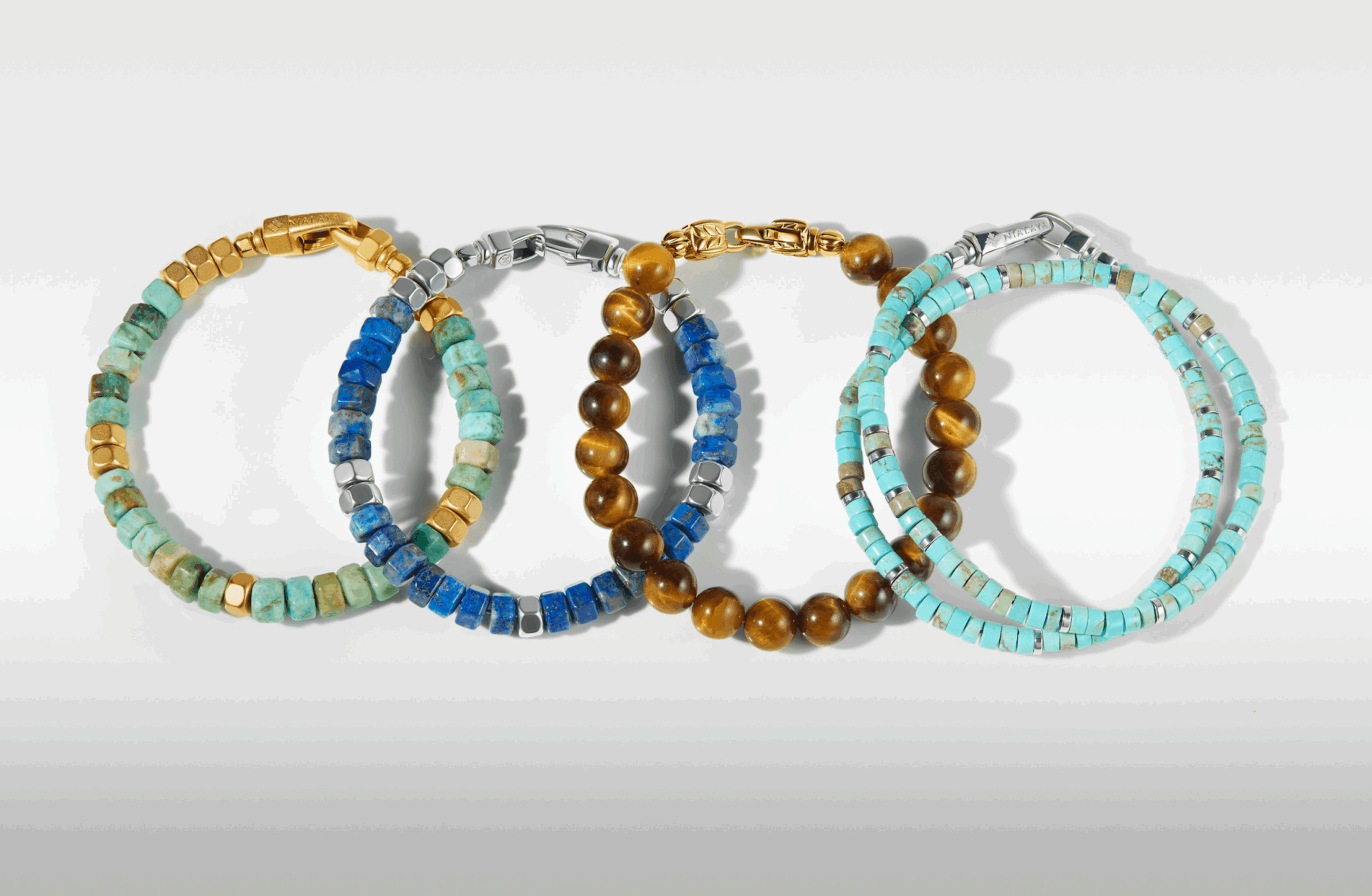 Four beaded bracelets in gold, silver, blue, and turquoise colors arranged in a row on a white background.