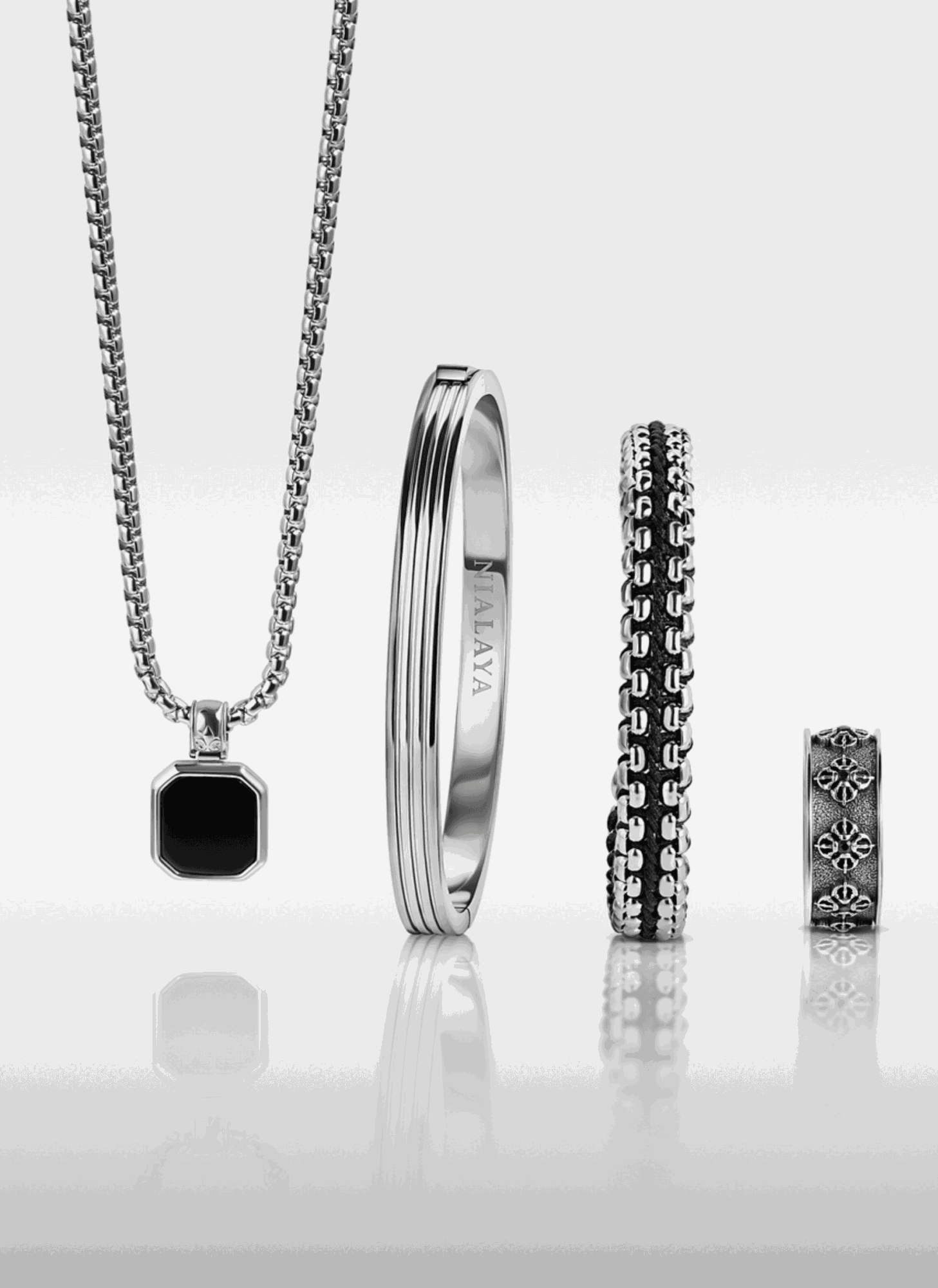 Set of jewelry including a chain necklace with a black pendant, a silver ring, two black and silver bracelets, and a small silver ring.