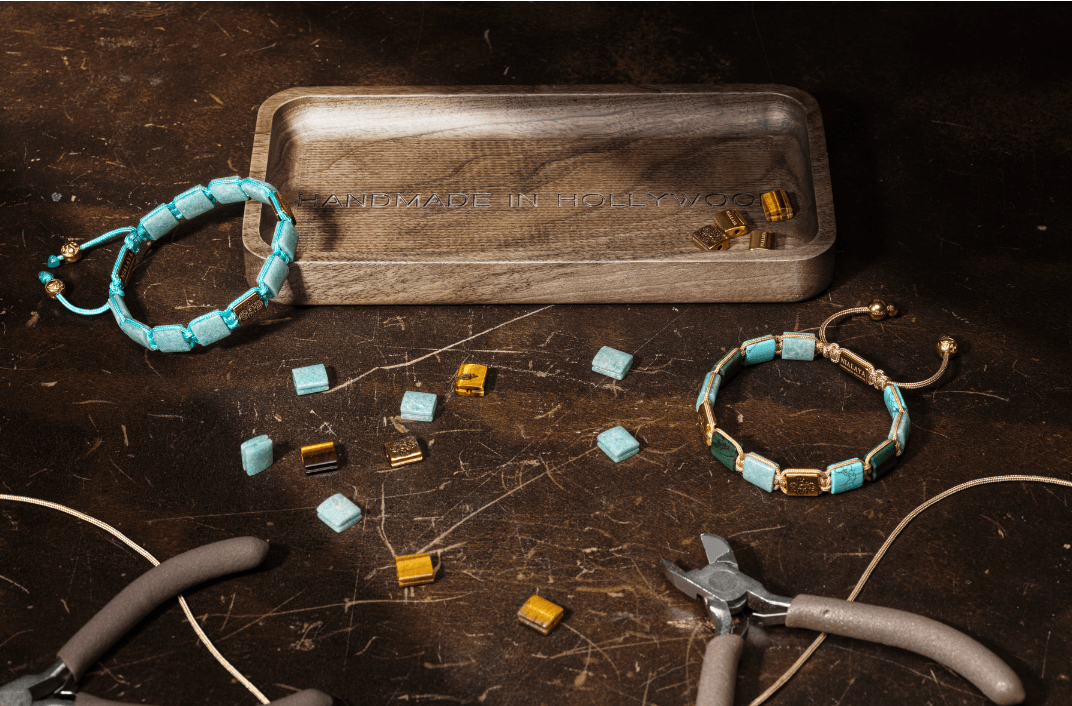 Beaded jewelry and scattered small beads on a dark wooden surface with tools nearby.
