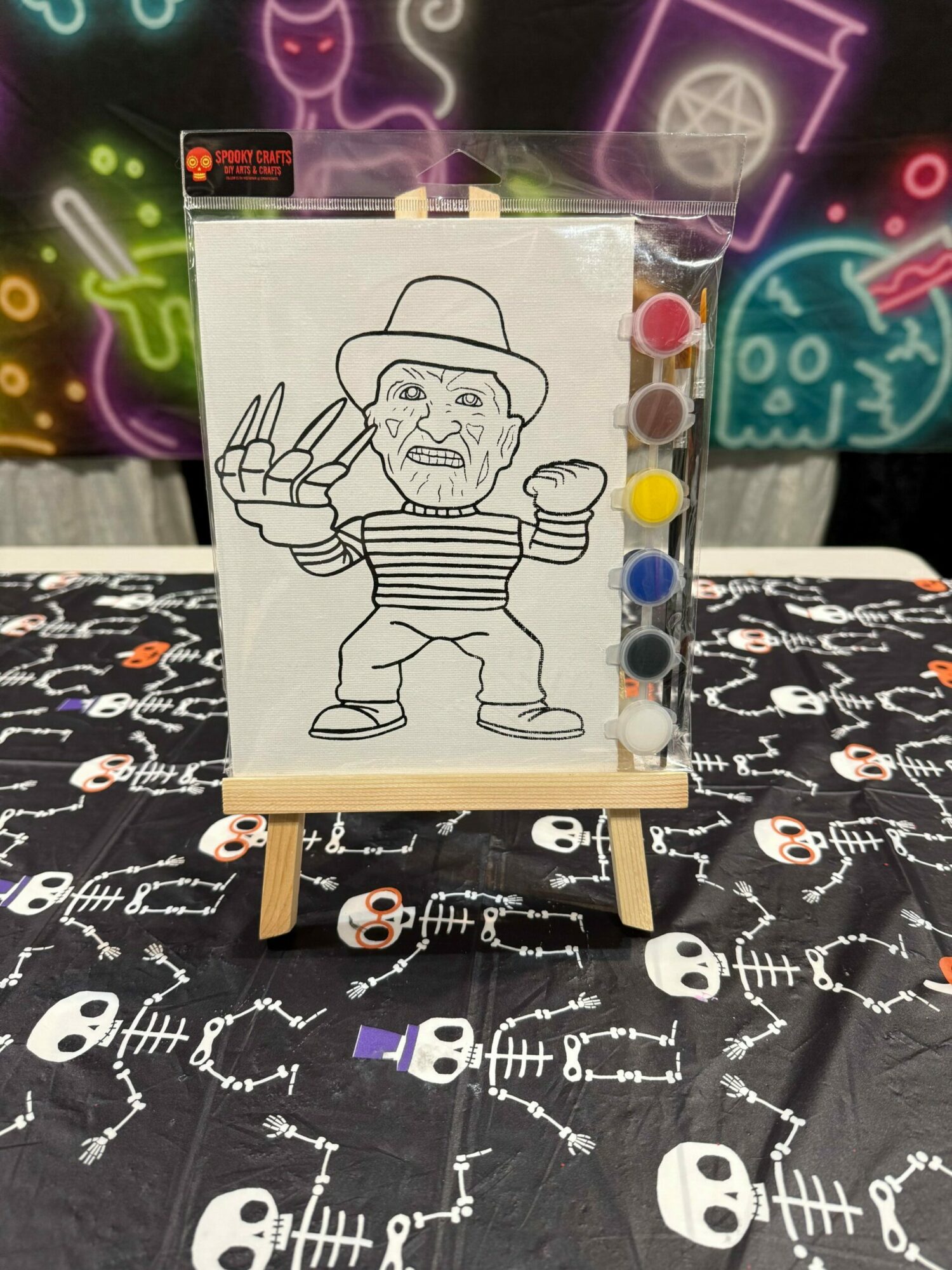 Black and white drawing of a person with a hat, striped shirt, and gloves, making a peace sign, pinned to a board.