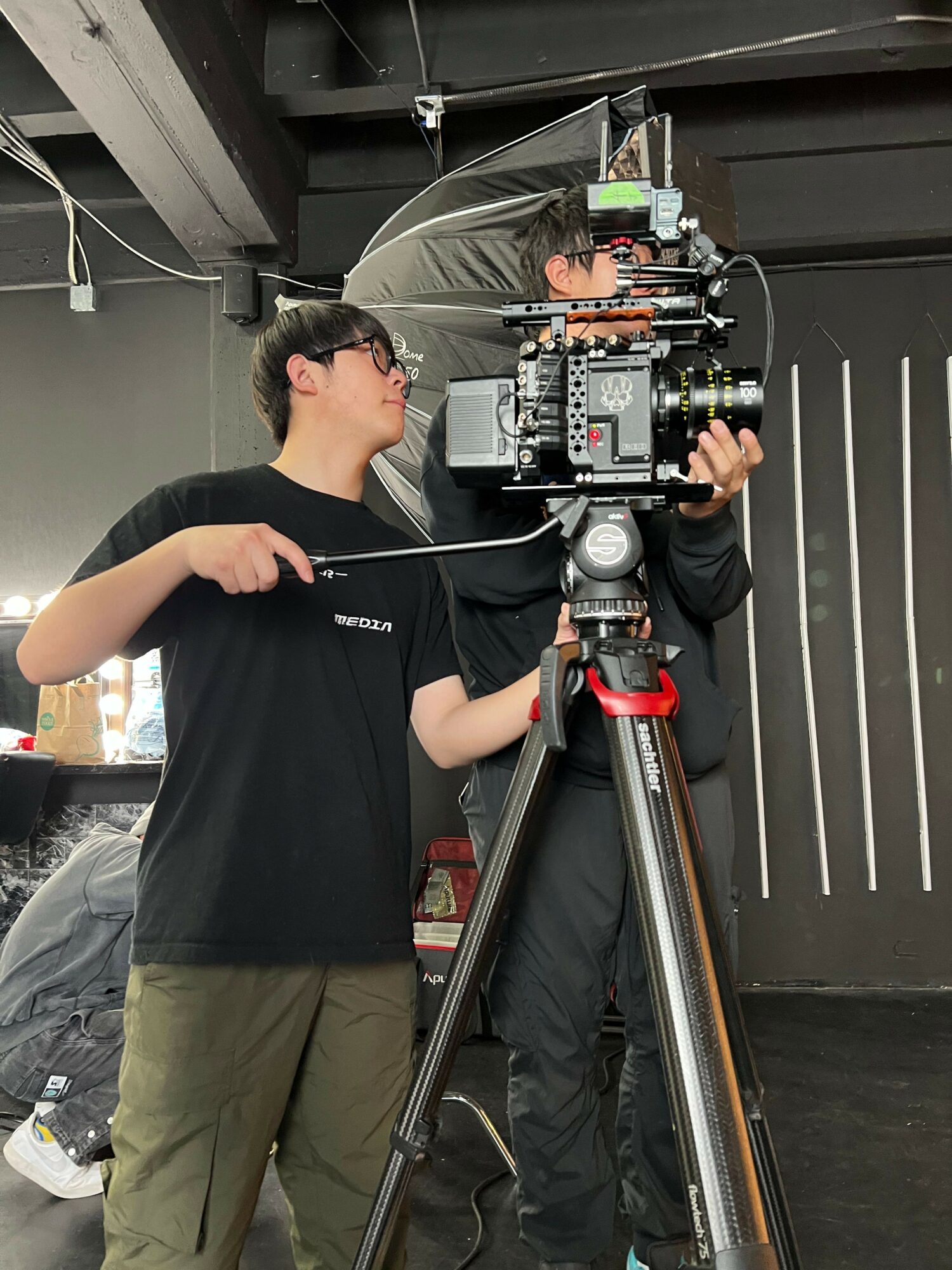 Person operating a professional camera on a tripod, adjusting settings in an indoor environment.